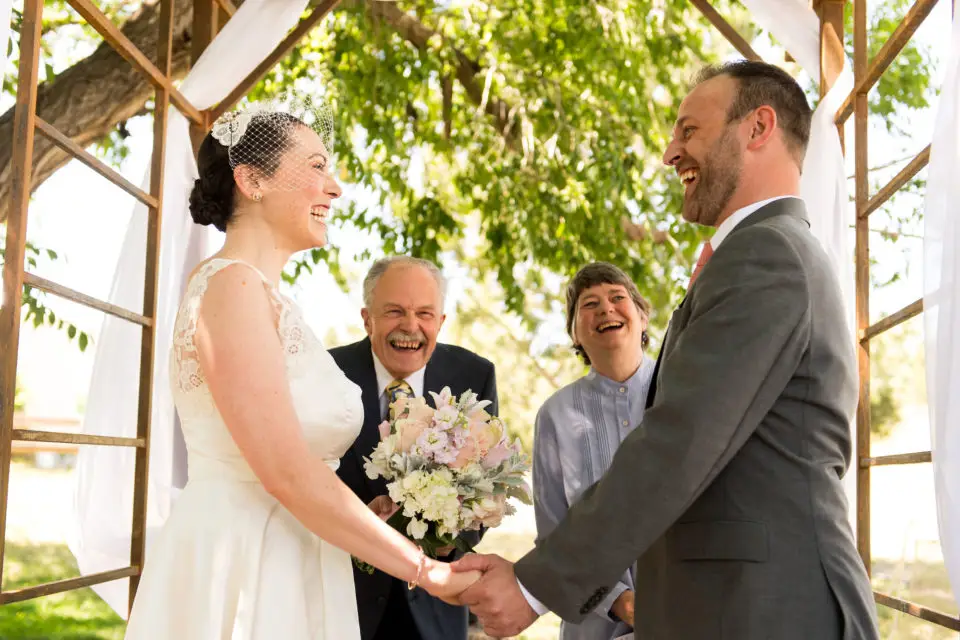 A couple holds hands during a backyard wedding ceremony in Colorado.