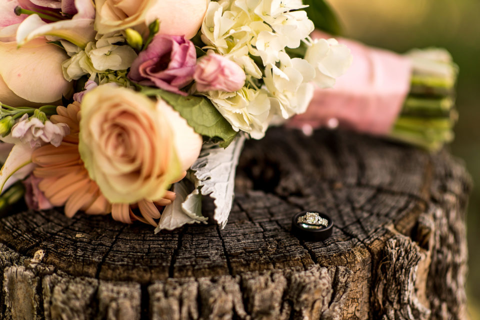 Wedding rings sit beside the bride's bouquet.