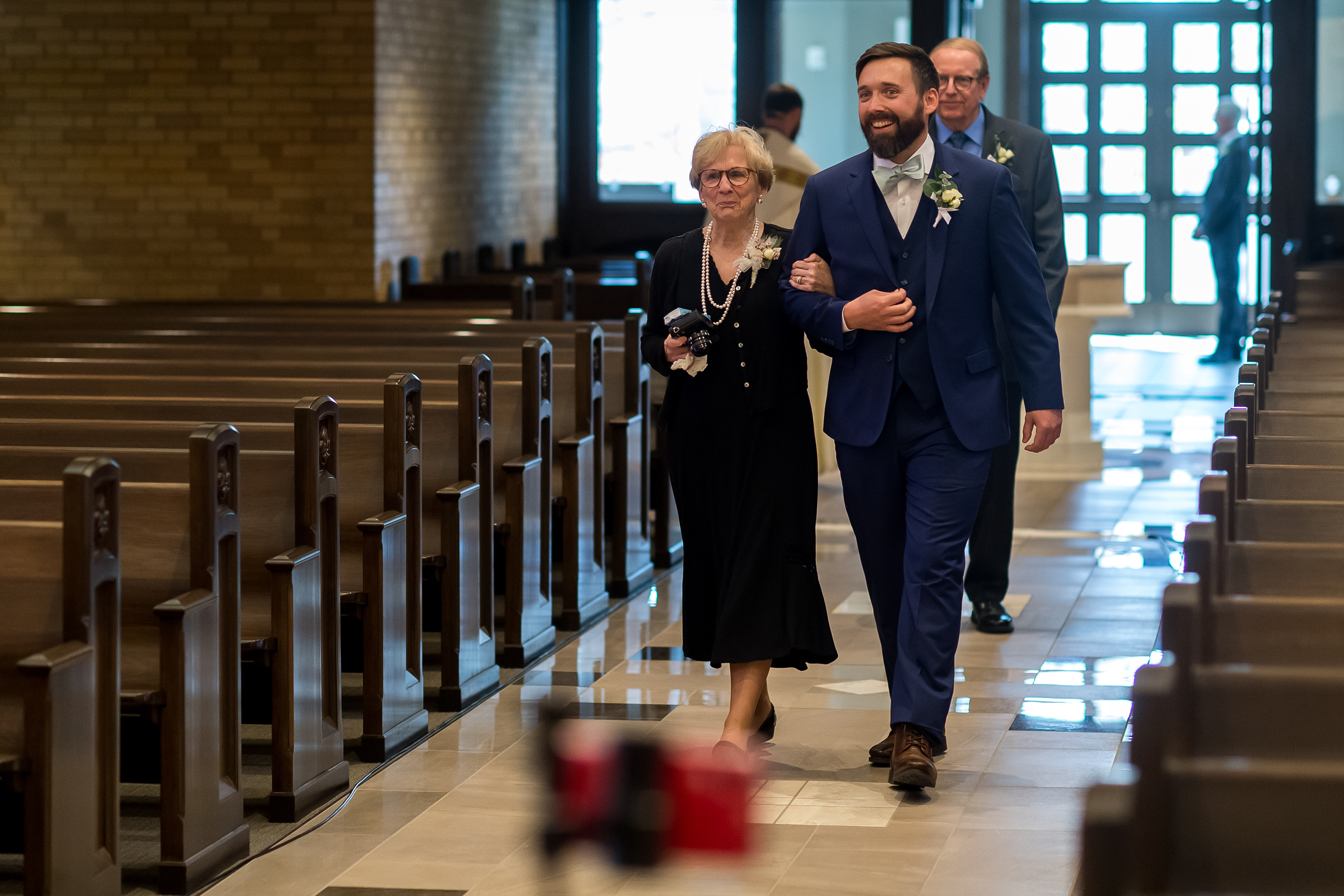 Groom walks his mother down the aisle during a wedding Mass at Our Lady of Lourdes Catholic Church in Denver, Colorado.