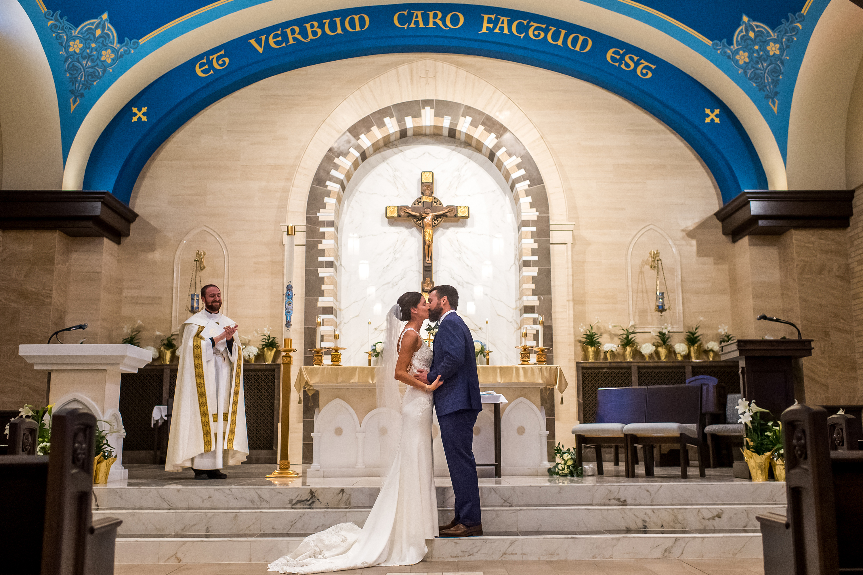 Bride and groom kiss at a Catholic wedding Mass at Our Lady of Lourdes Catholic Church in Denver, Colorado.