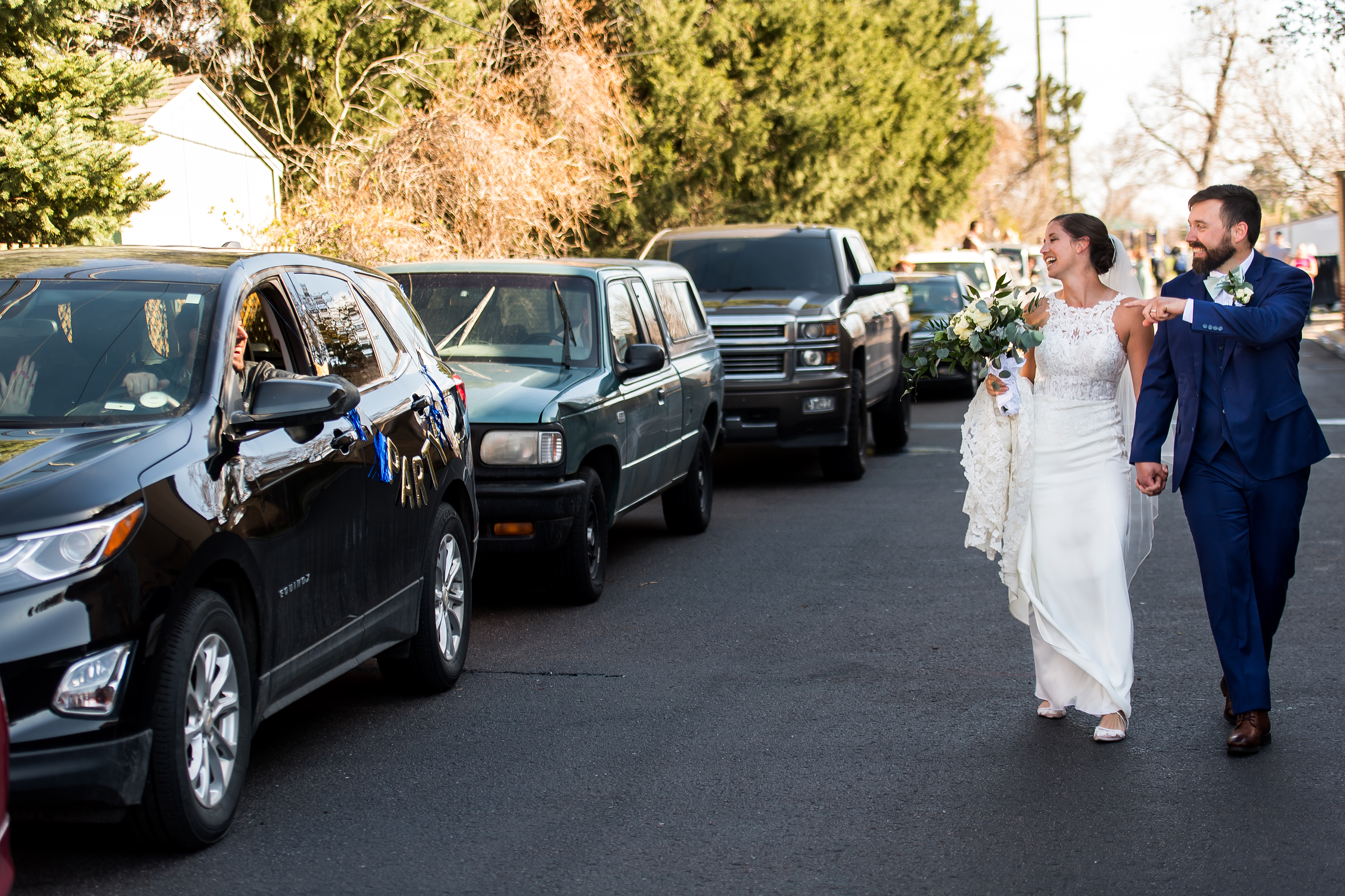 Friends line up in their cars to congratulate bride and groom after their wedding at Our Lady of Lourdes Catholic Church in Denver, Colorado.