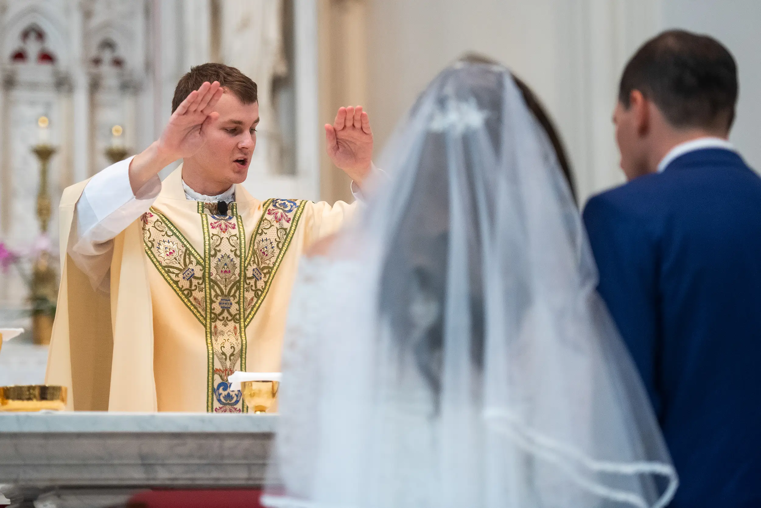 A priest prays over the bride and groom during their wedding at the Cathedral Basilica of the Immaculate Conception in Denver, Colorado.