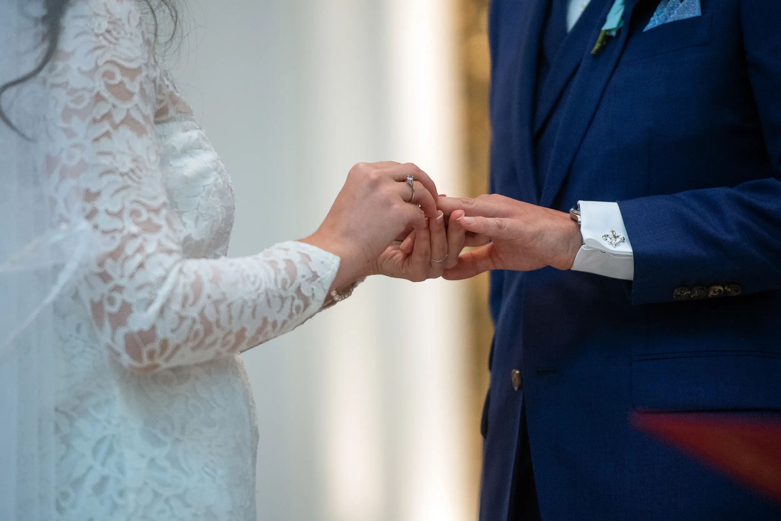 Bride puts a ring onto the groom's finger during their wedding at the Cathedral Basilica of the Immaculate Conception in Denver, Colorado.
