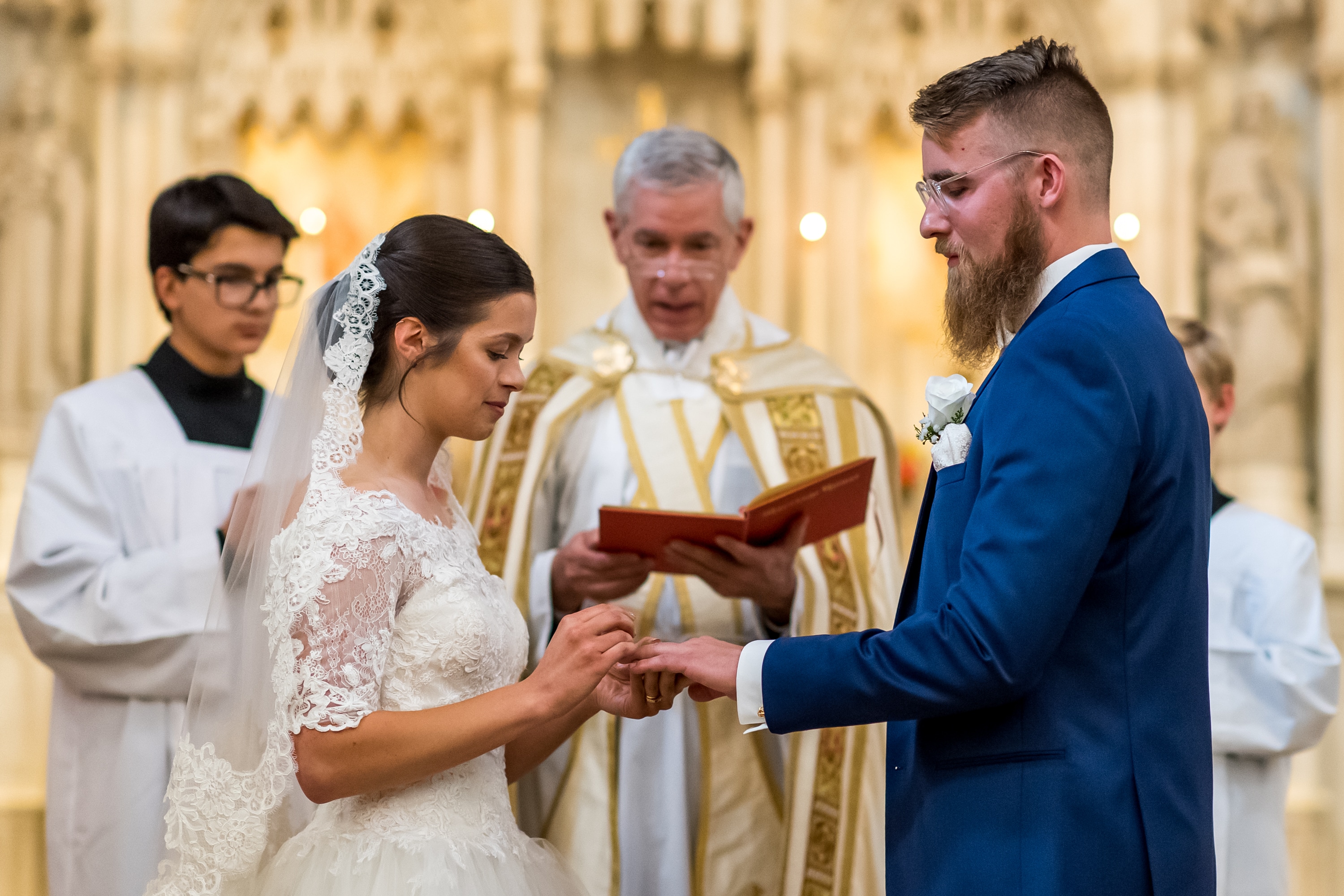 Bride puts on the ring of the groom at Our Lady of Mt. Carmel in Littleton, Colorado.