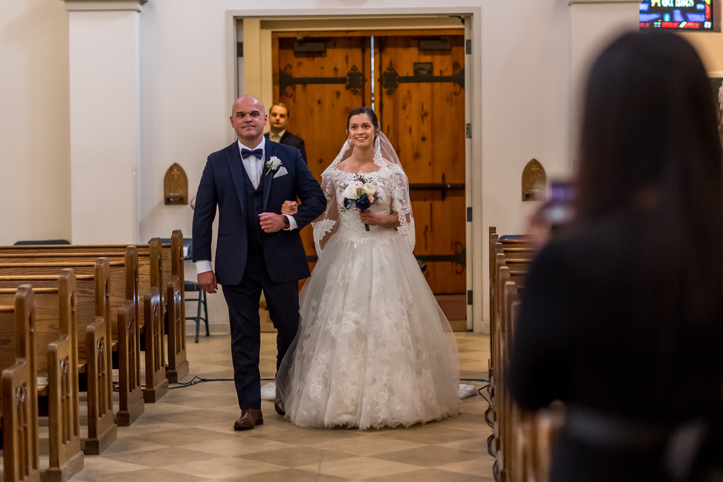 Bride walks down the aisle of her wedding at Our Lady of Mt. Carmel in Littleton, Colorado.