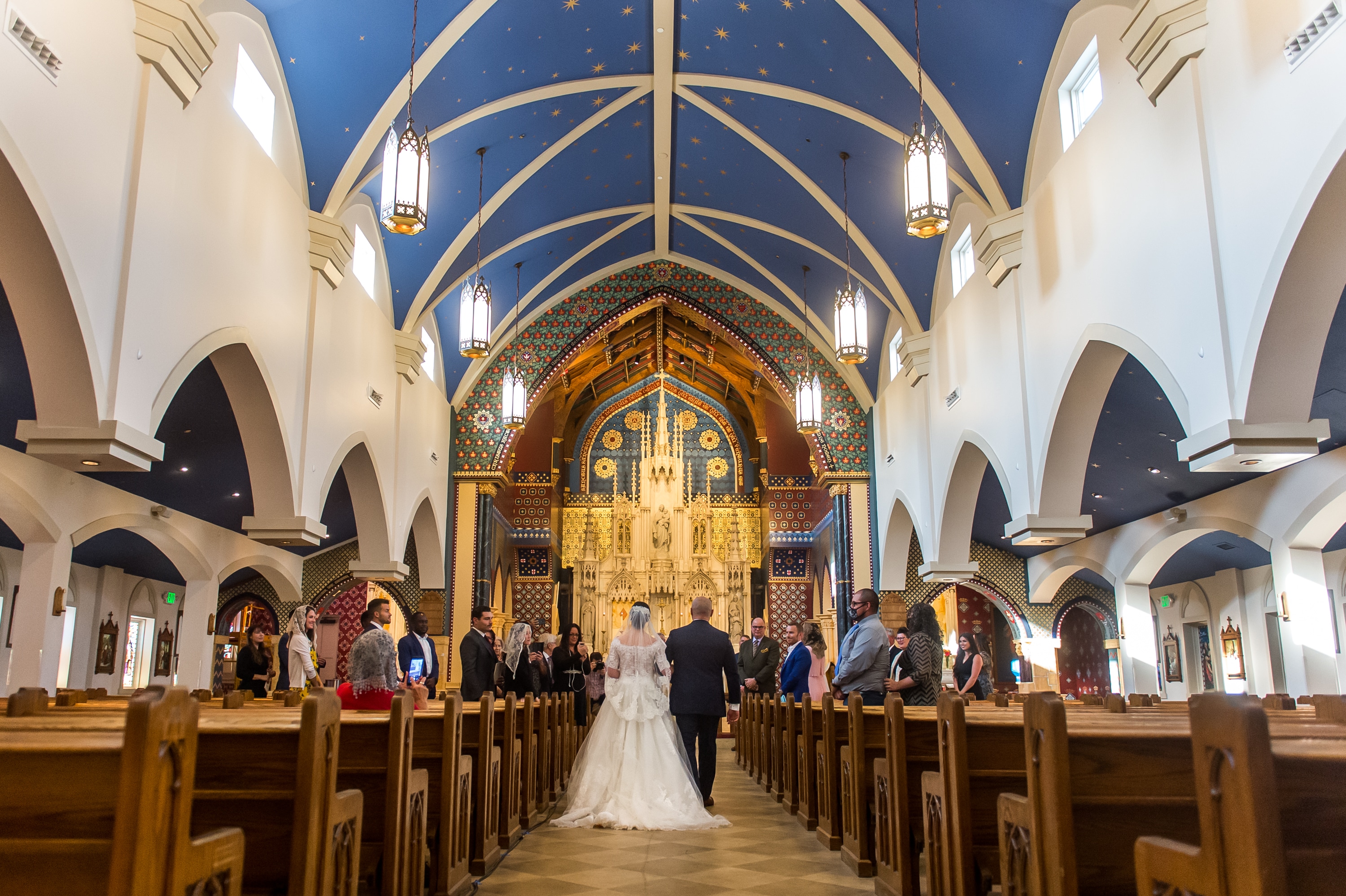 Bride walks down the aisle with her father during a wedding at Our Lady of Mt. Carmel in Littleton, Colorado.
