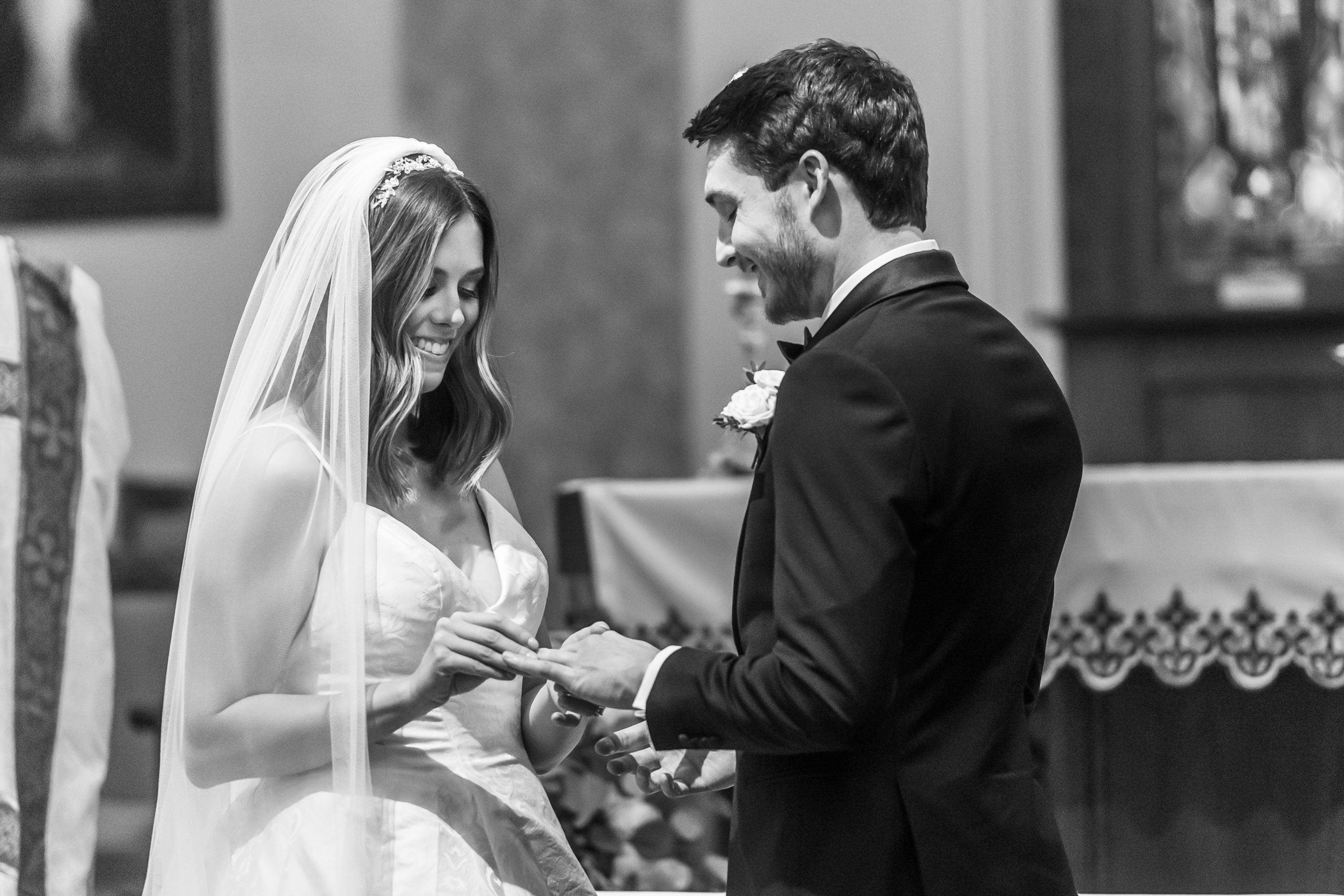 Bride puts on ring on groom during a Blessed Sacrament Denver wedding ceremony.