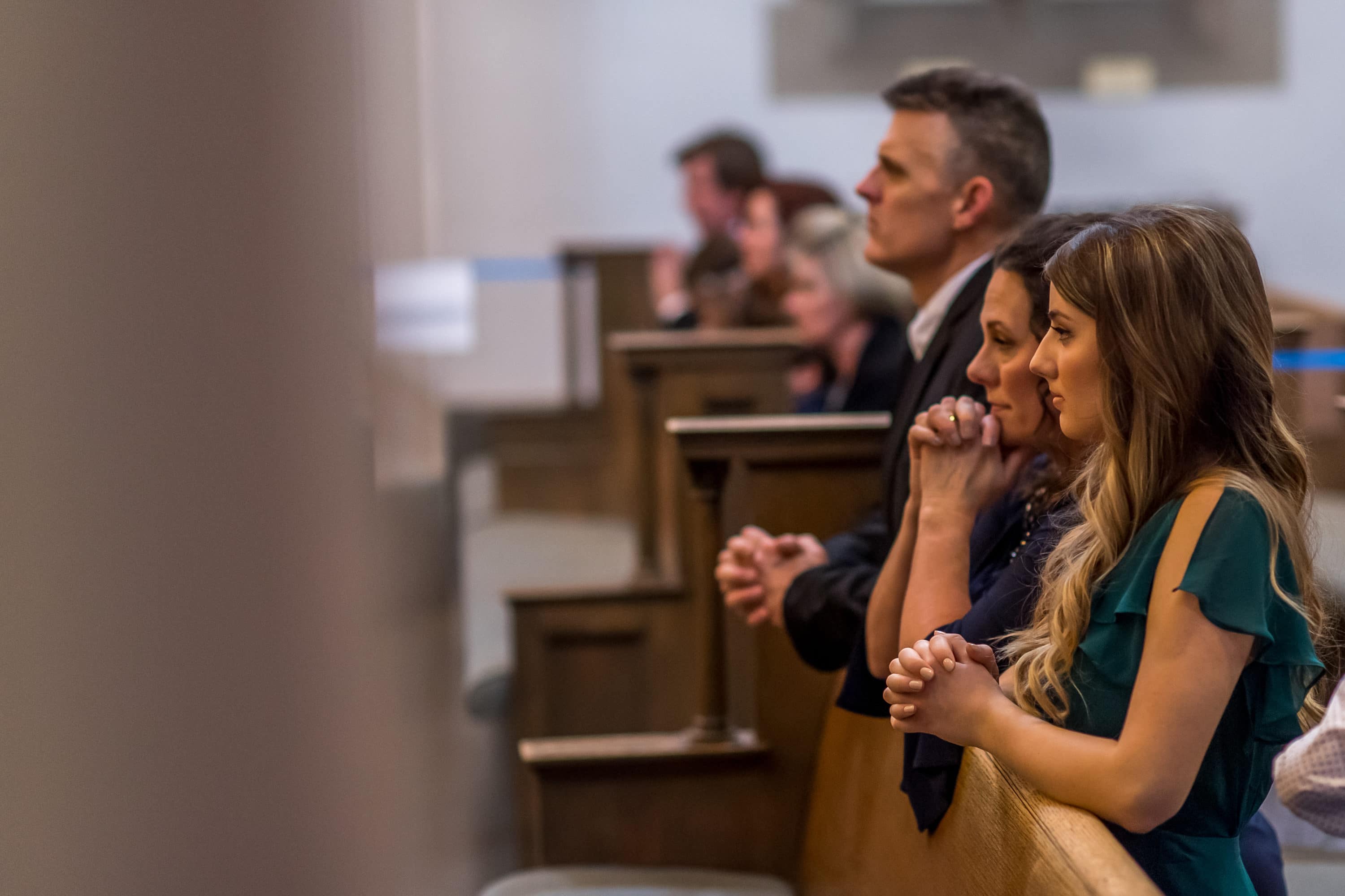Family and friends kneel during a Blessed Sacrament Denver wedding photos