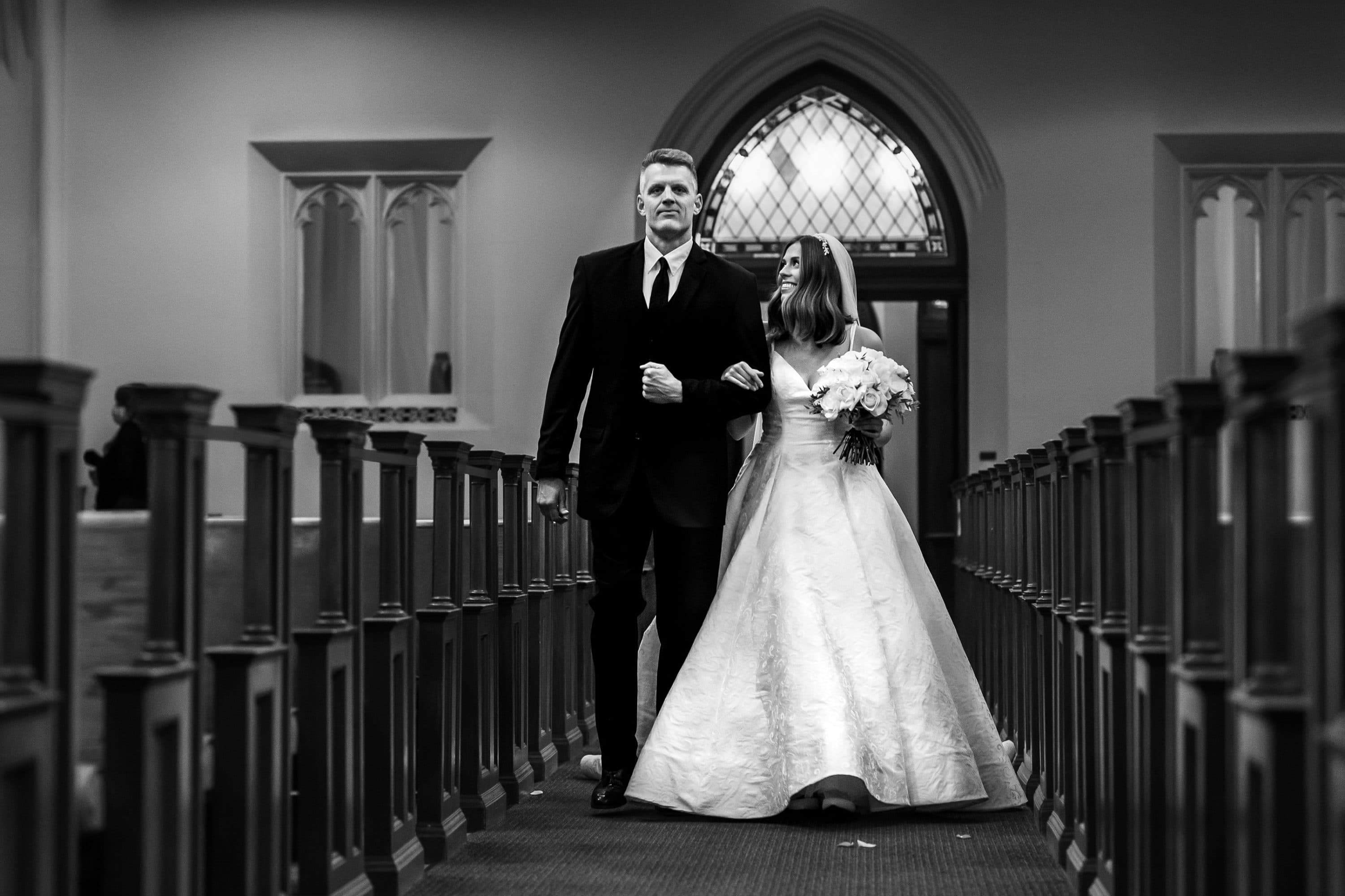 Bride and bride's father walk down the aisle at Blessed Sacrament Catholic Church in Denver, Colorado.