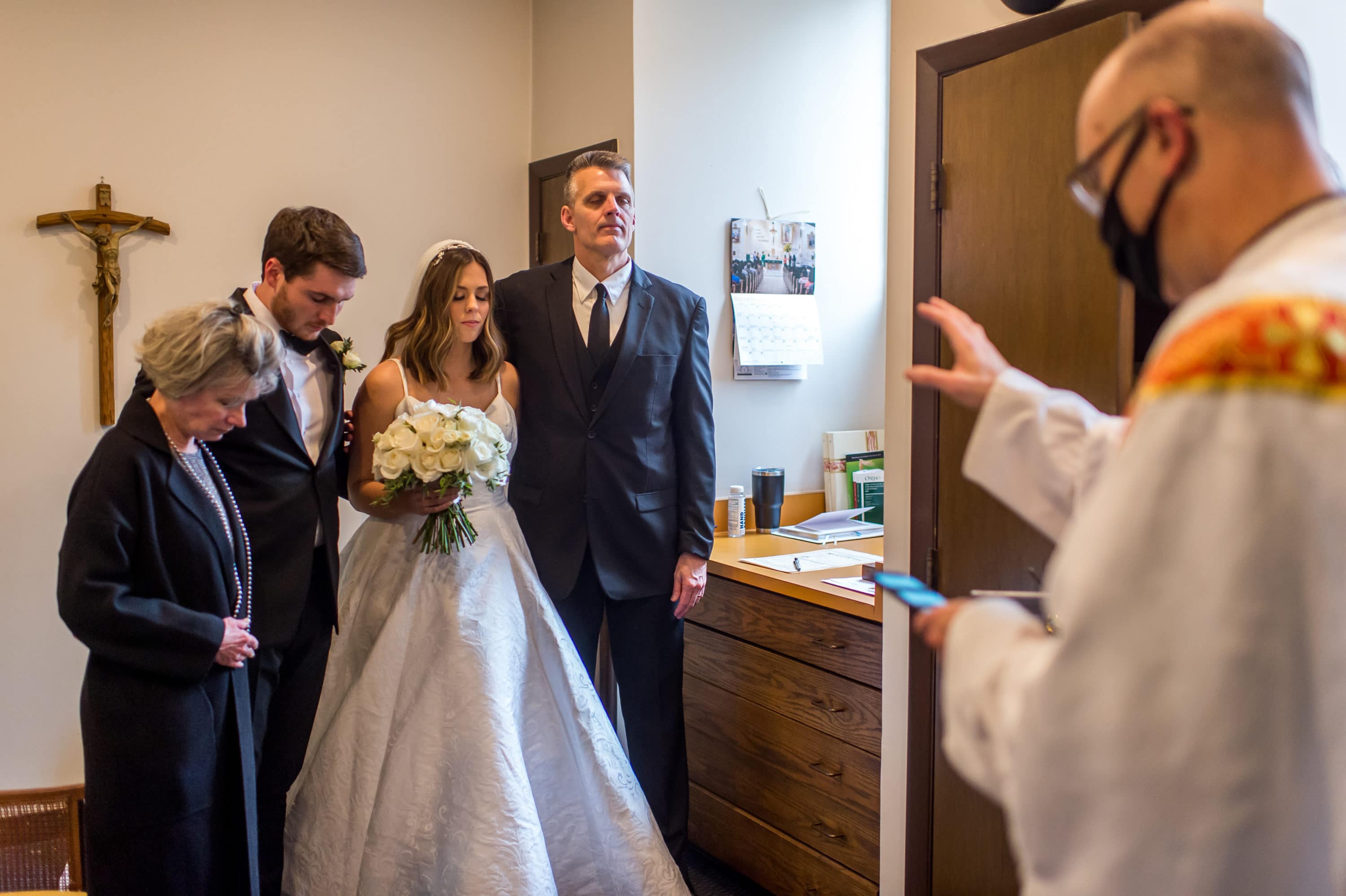 A priest blesses the bride, groom and family after a Blessed Sacrament Denver wedding ceremony.