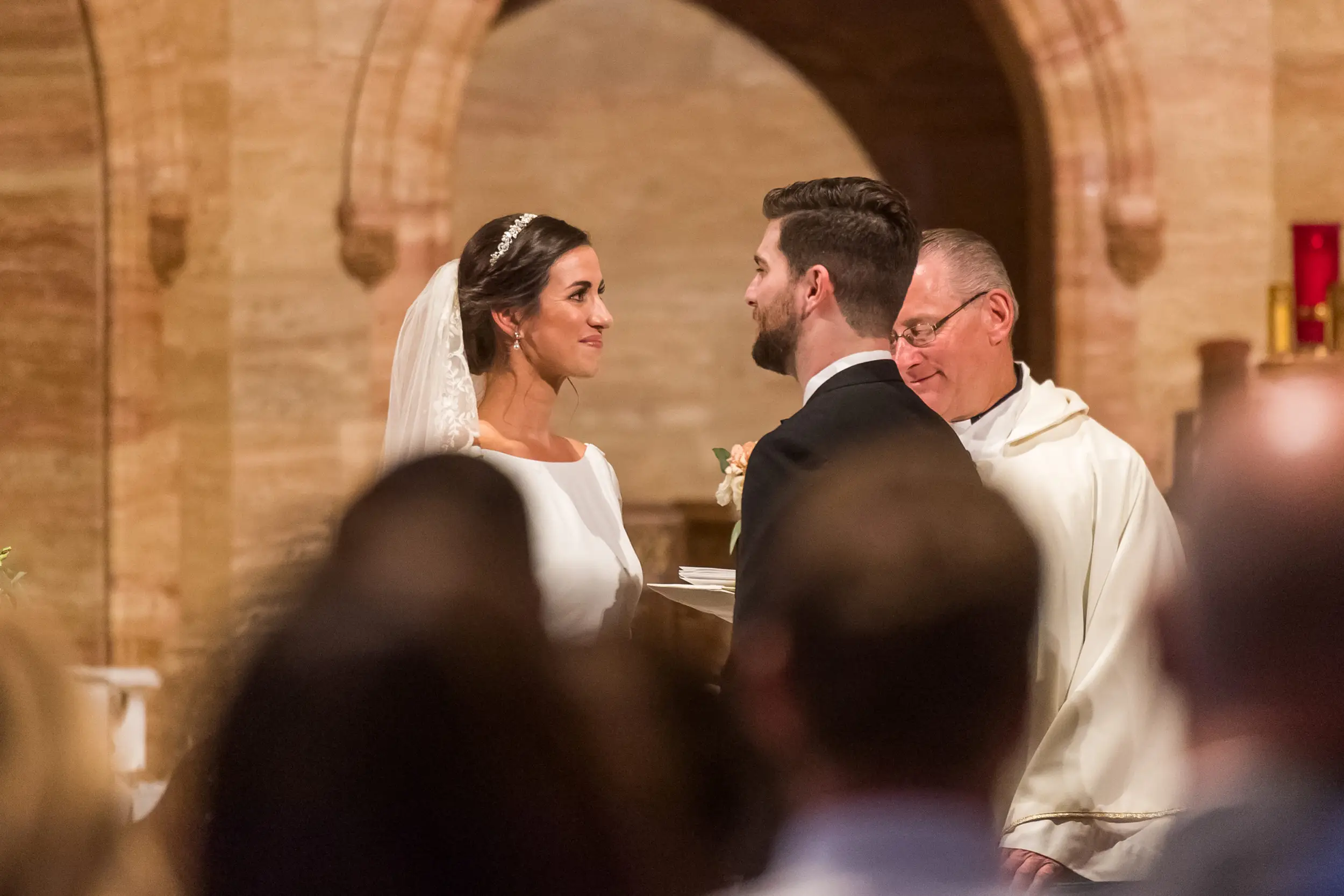 Bride and groom look at each other during their Holy Ghost Church Denver wedding Mass in Denver, Colorado.