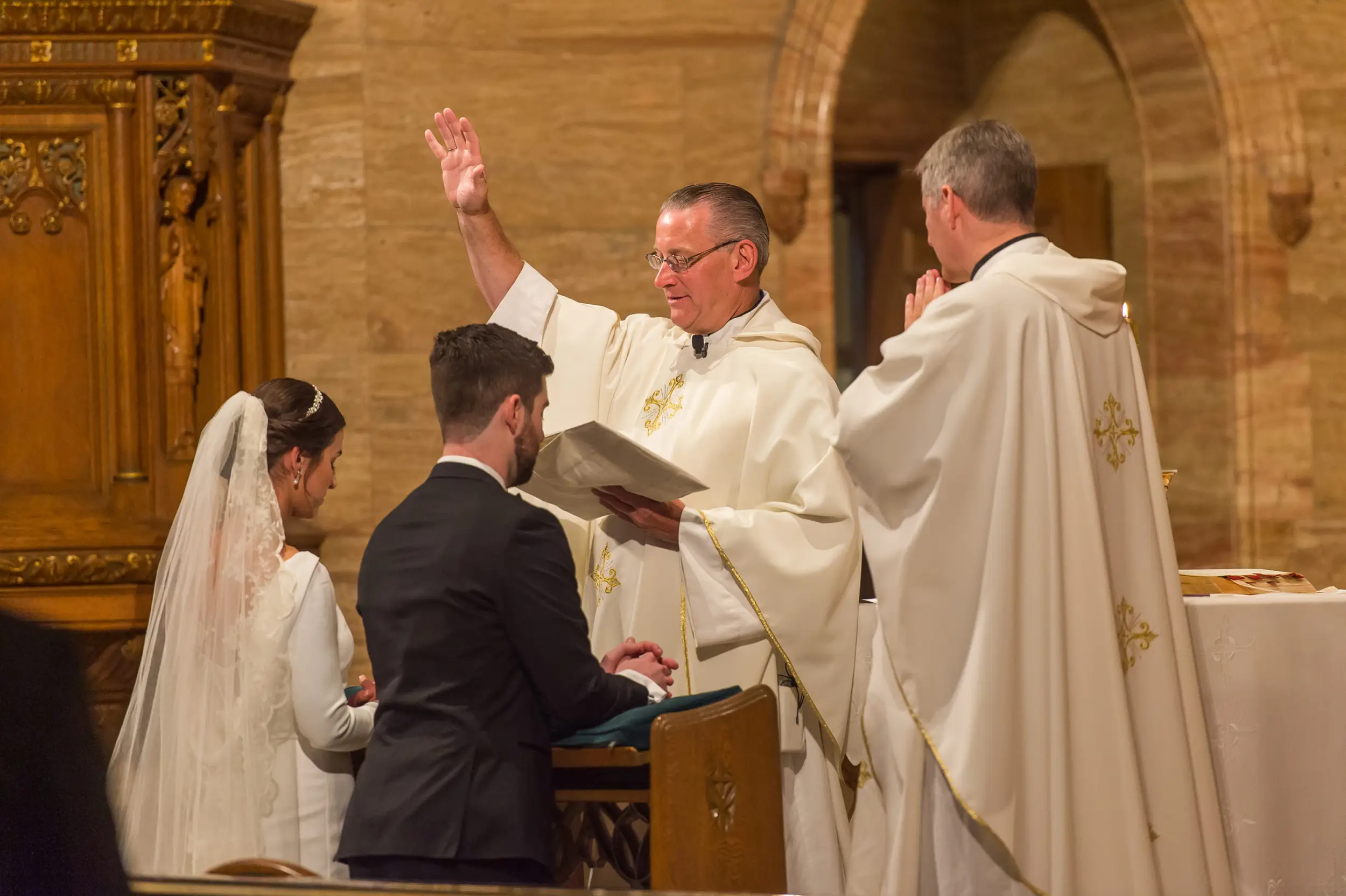 Bride and groom are blessed during their Holy Ghost Church Denver wedding Mass in Denver, Colorado.