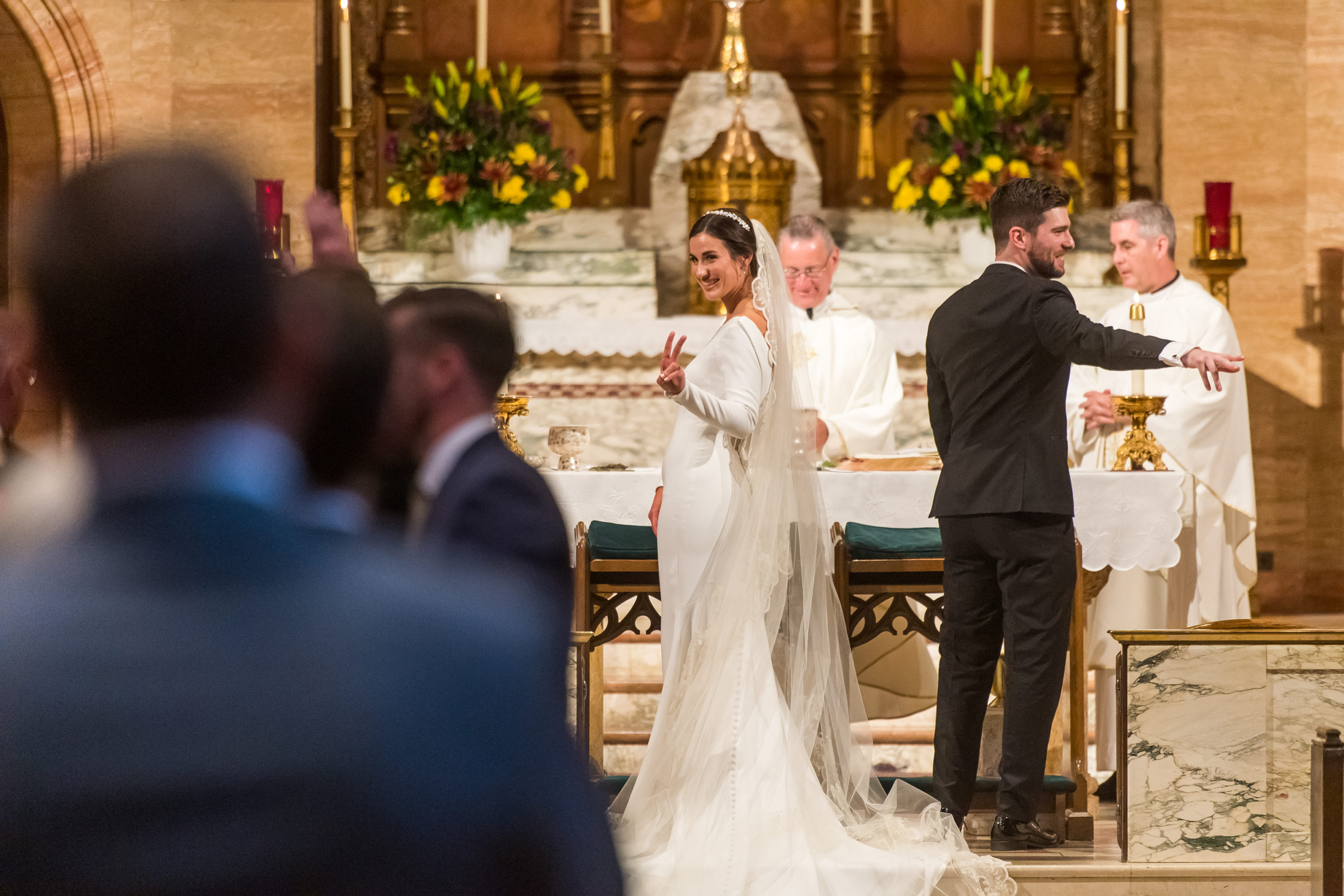 Bride flashes sign of peace during her wedding at Holy Ghost Church in Denver, Colorado.