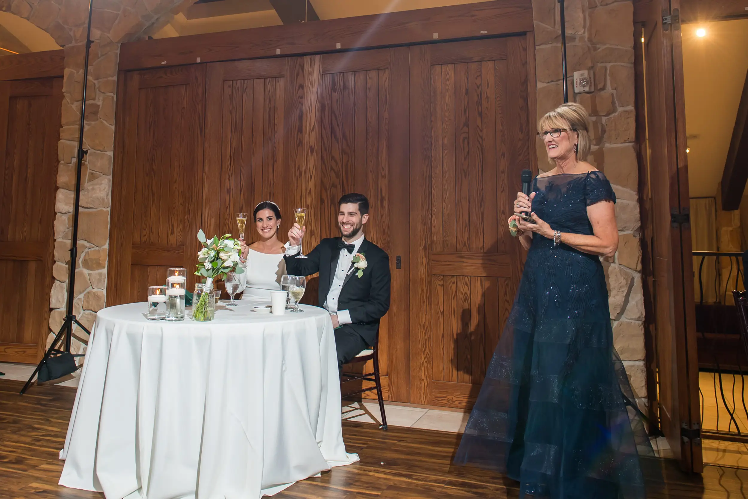 Bride and groom smile during toasts at Baldoria on the Water wedding venue in Lakewood, Colorado.