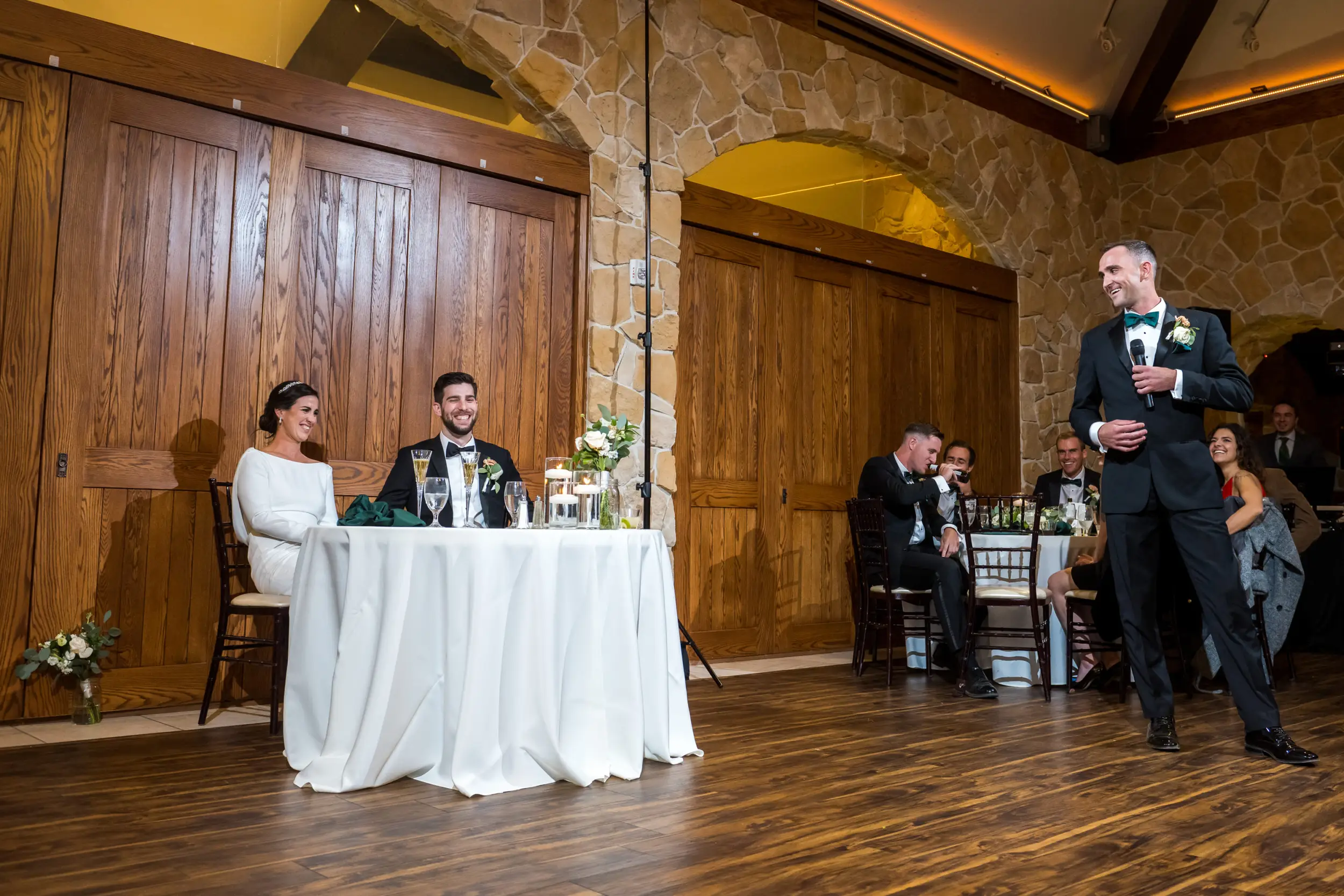 Bride and groom smile during toasts at Baldoria on the Water wedding venue in Lakewood, Colorado.
