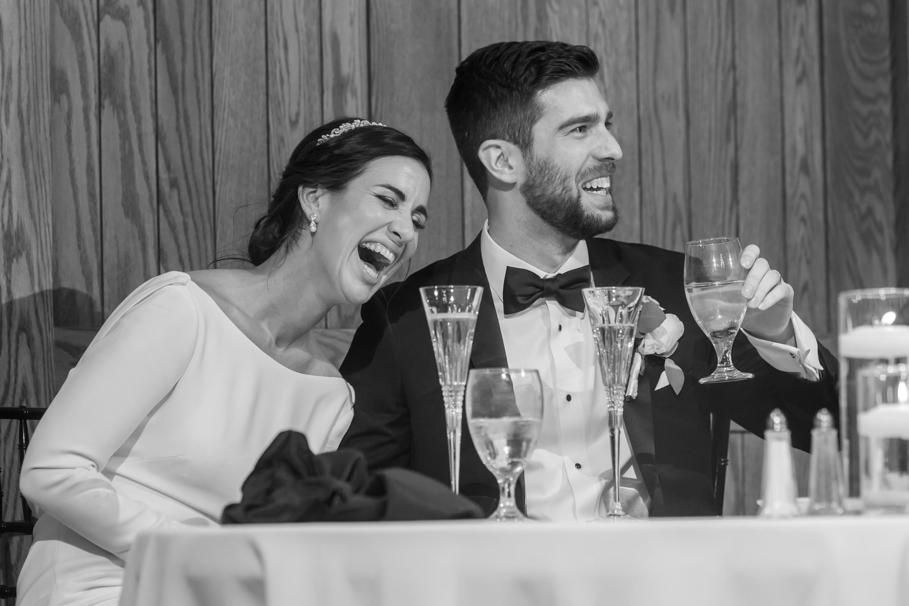 Bride and groom laugh during toasts at Baldoria on the Water wedding venue in Lakewood, Colorado.