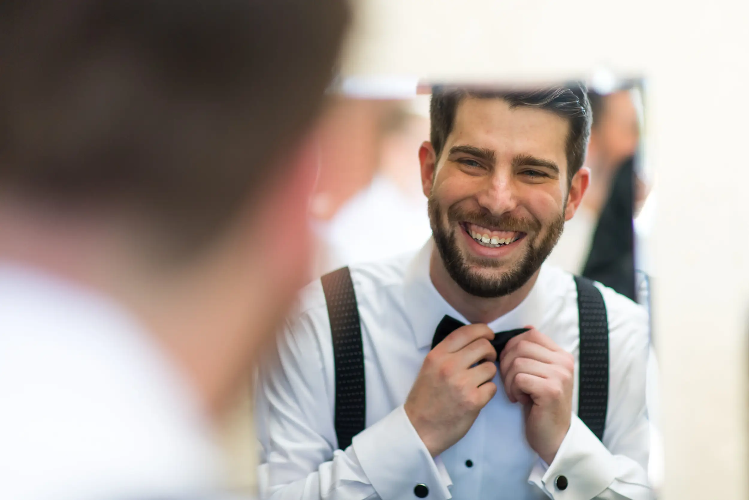 Groom puts on bow-tie at Baldoria on the Water in Lakewood, Colorado.