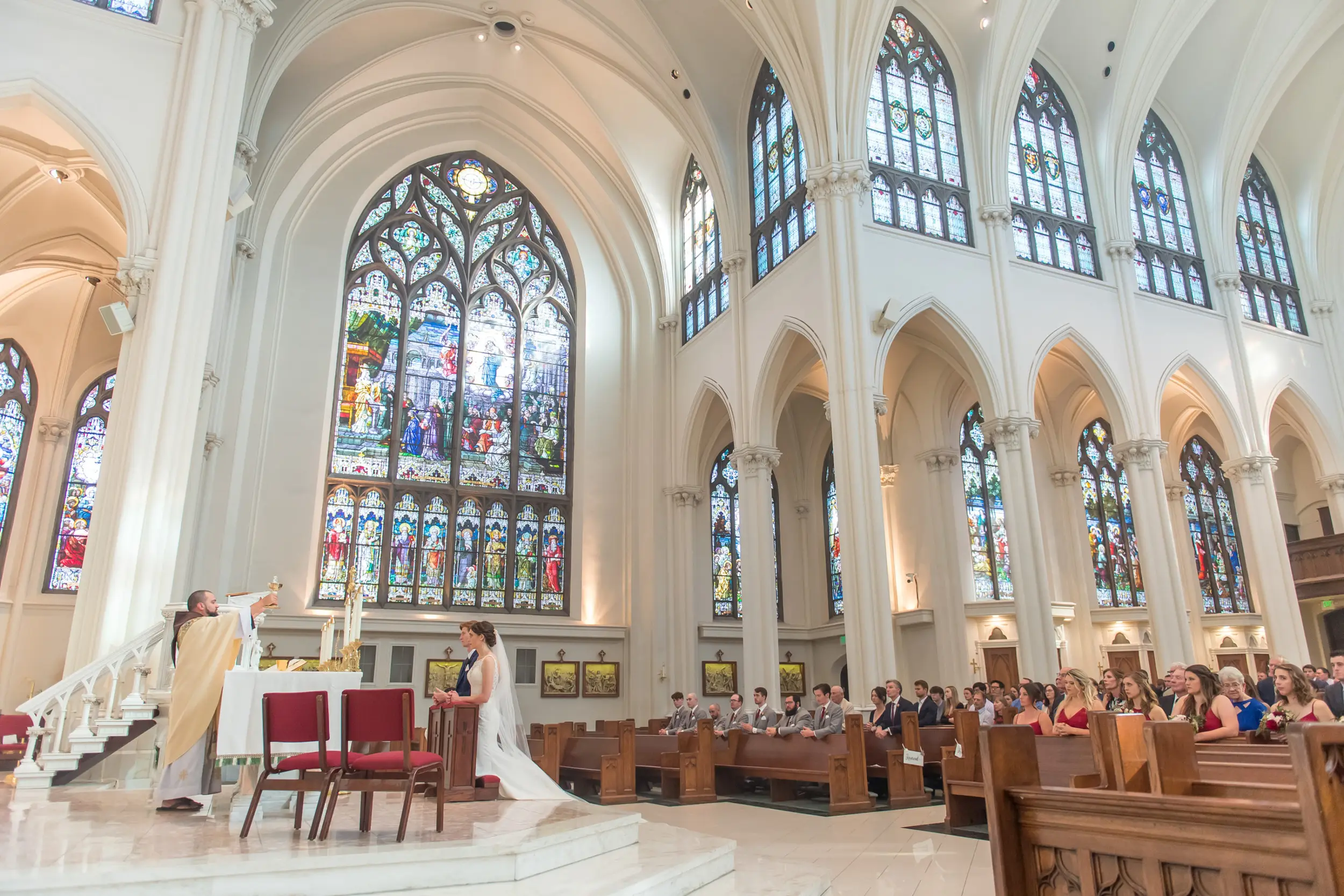The priest holds a chalice during a Cathedral Basilica of the Immaculate Conception wedding in Denver, Colorado.