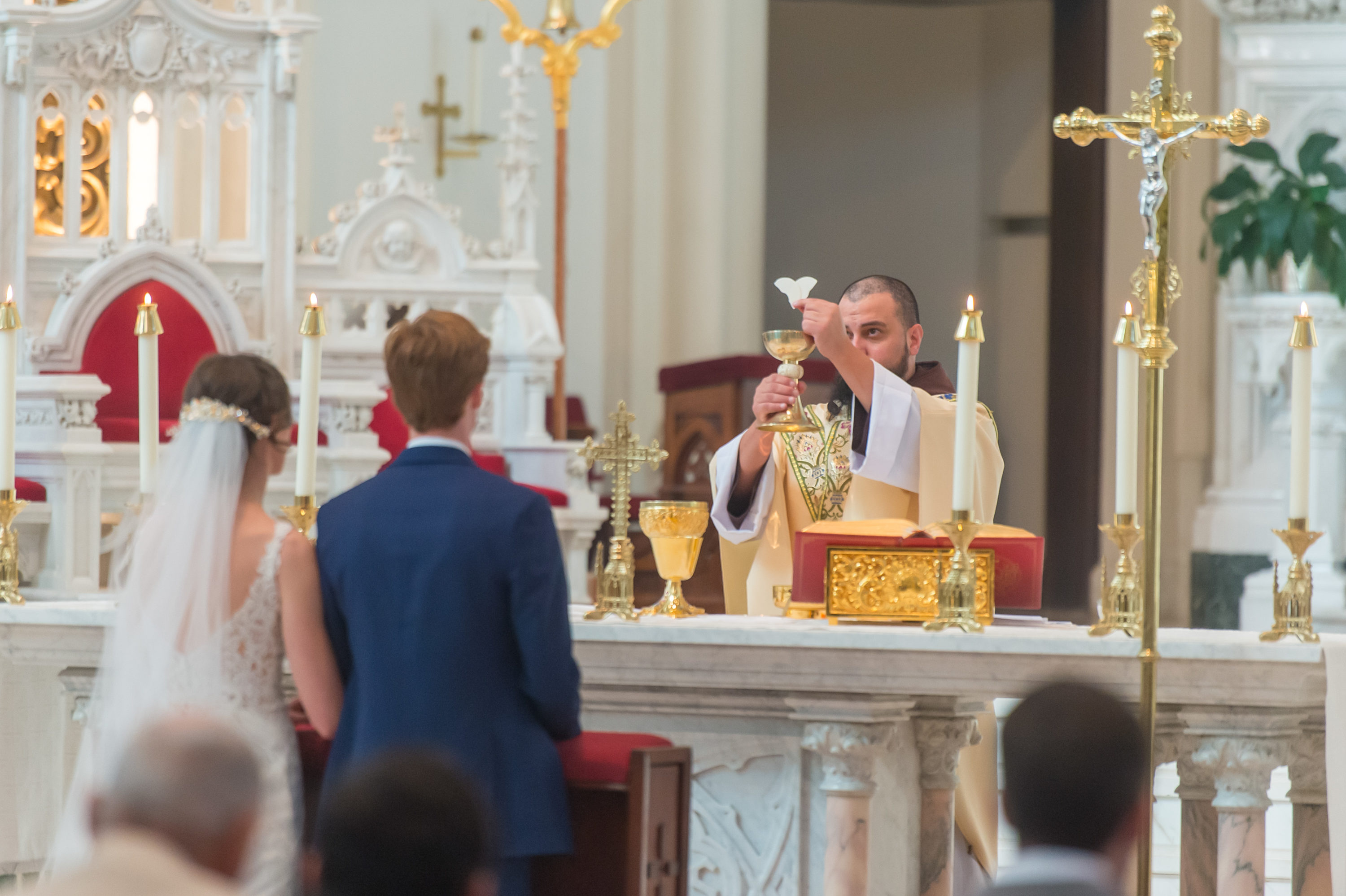 The priest holds consecrated host and wine during a Cathedral Basilica of the Immaculate Conception wedding in Denver, Colorado.