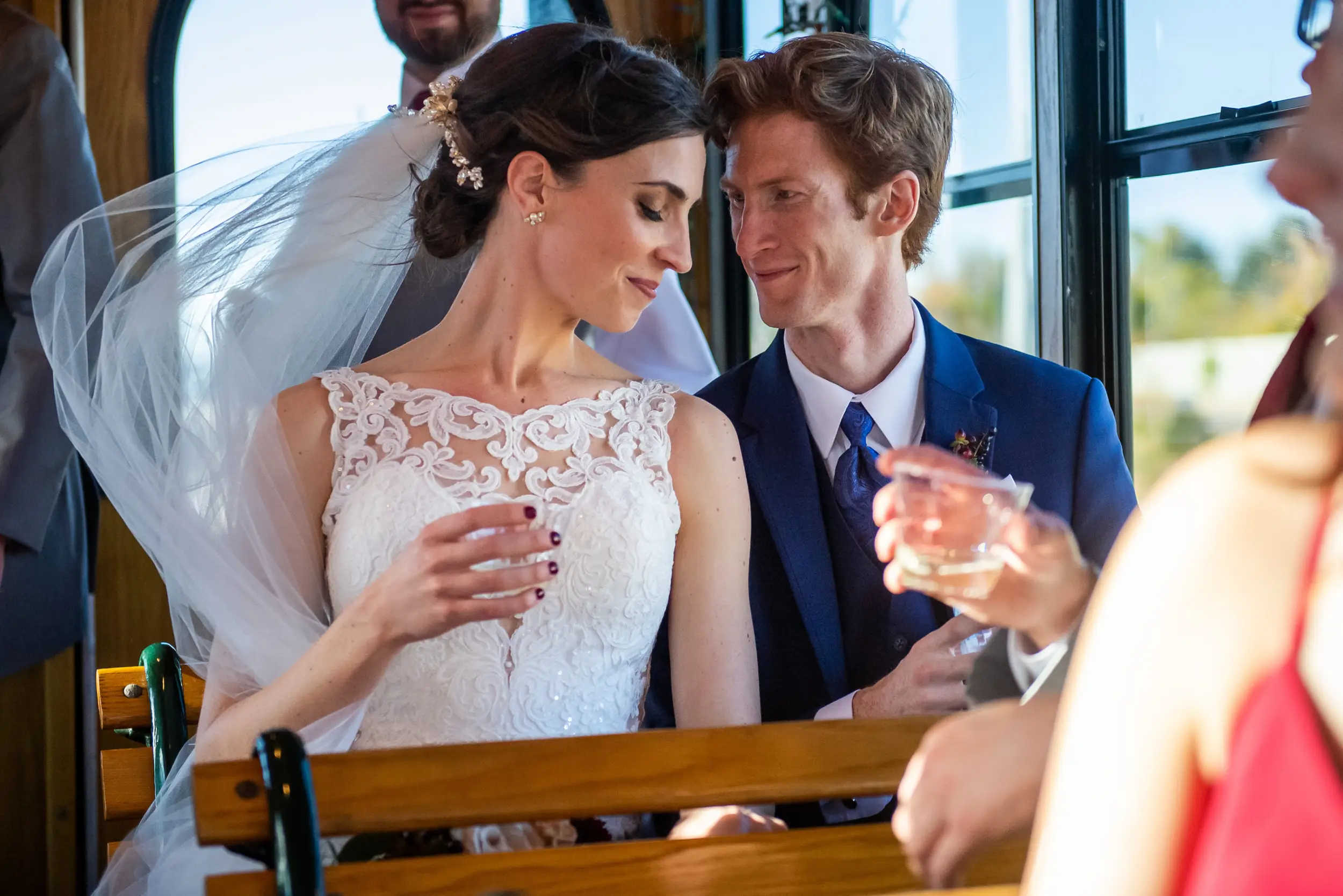 Bride and groom lean in to one another during a bus ride on their wedding day