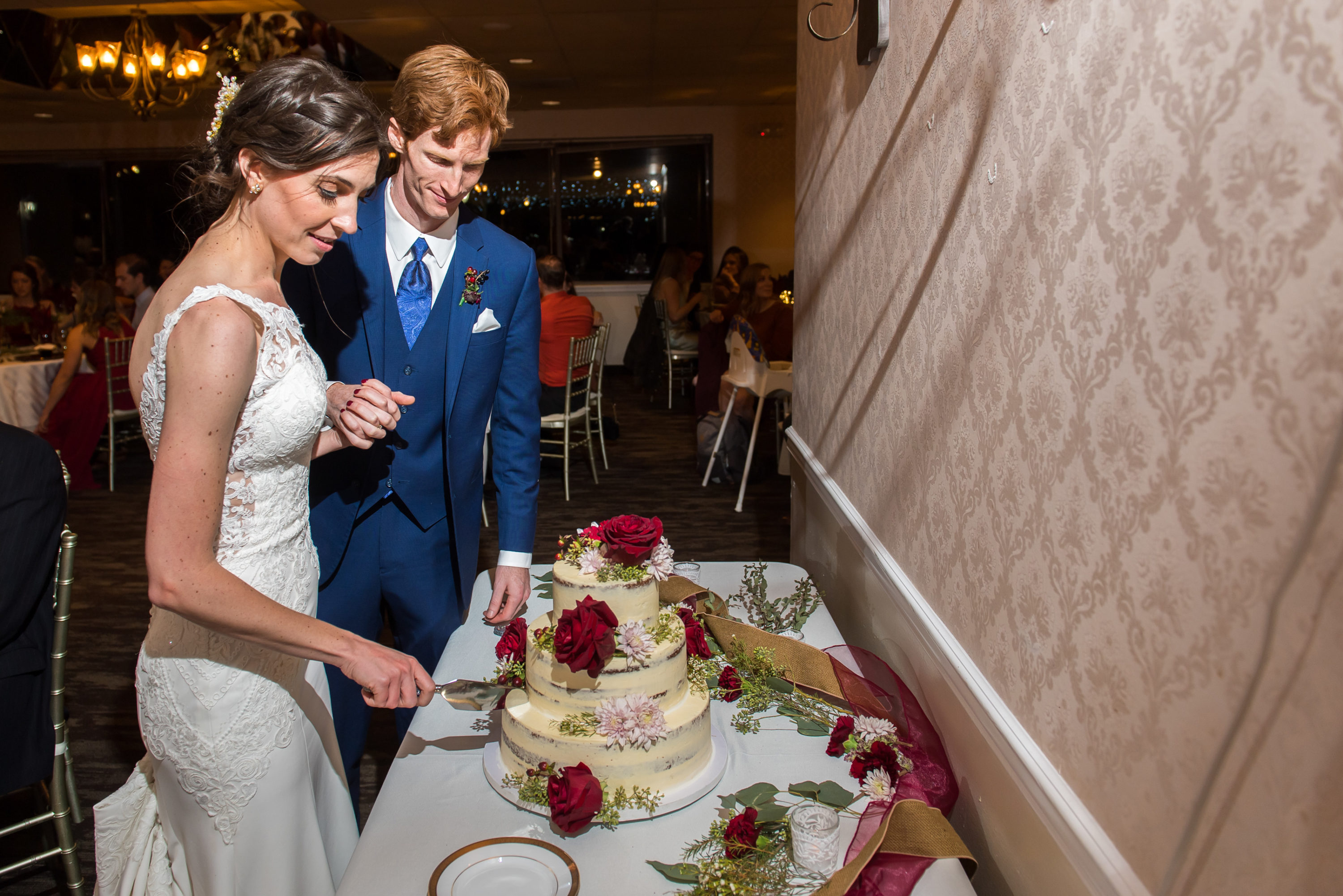 Bride and groom cut cake during a wedding reception at the Franciscan Event Center in Centennial, Colorado.