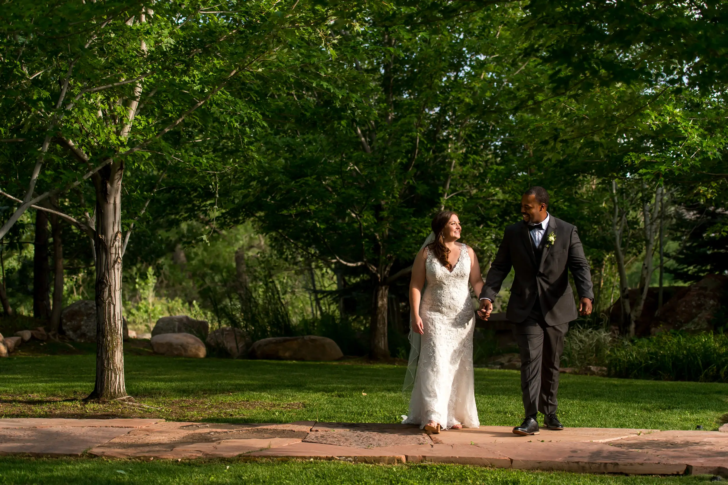 The bride and groom walk through the gardens during a Greenbriar Inn wedding in Boulder, Colorado.