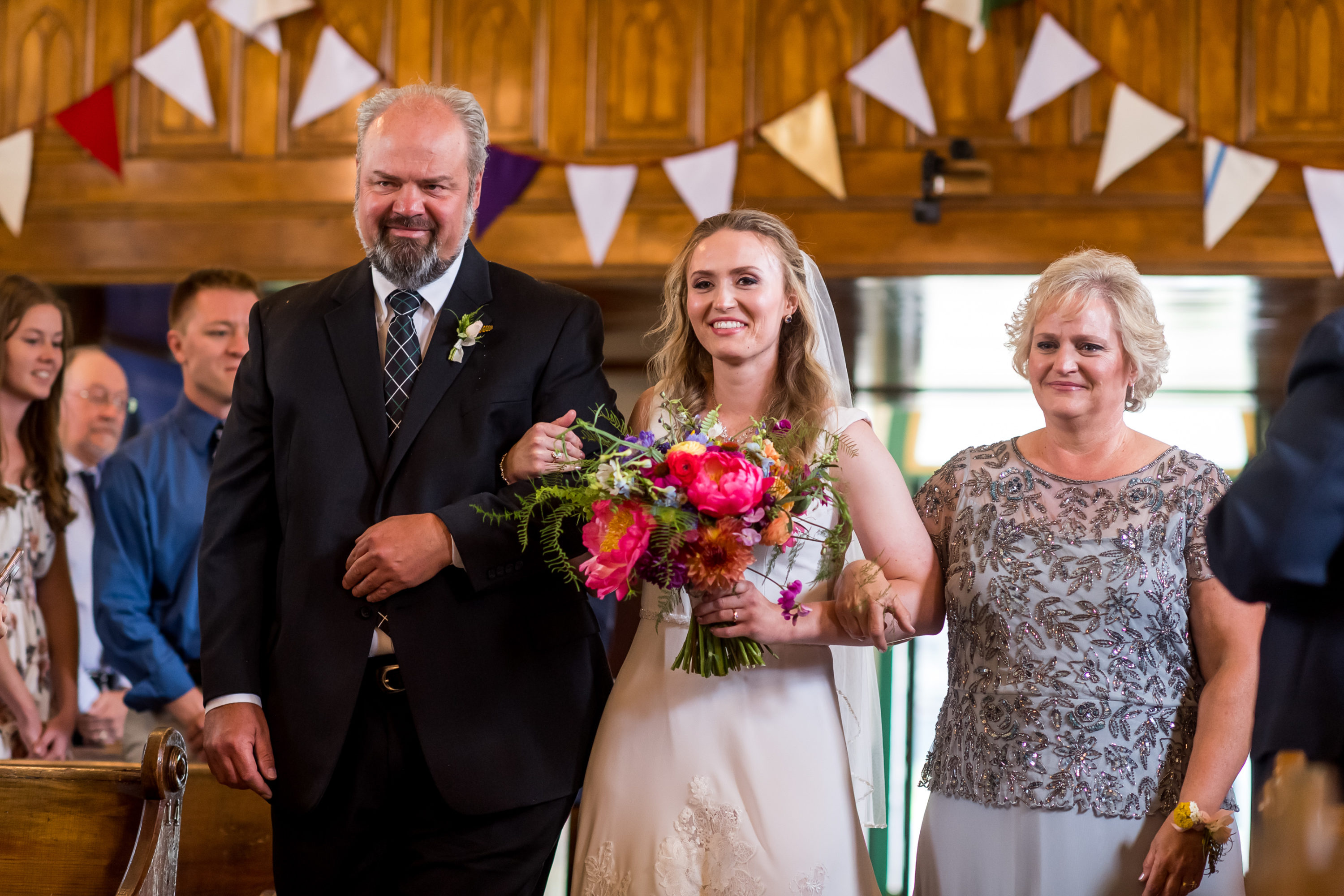 The bride and her mother and father walk down the aisle during their Telluride, Colorado, wedding at St. Patrick's Catholic Church.