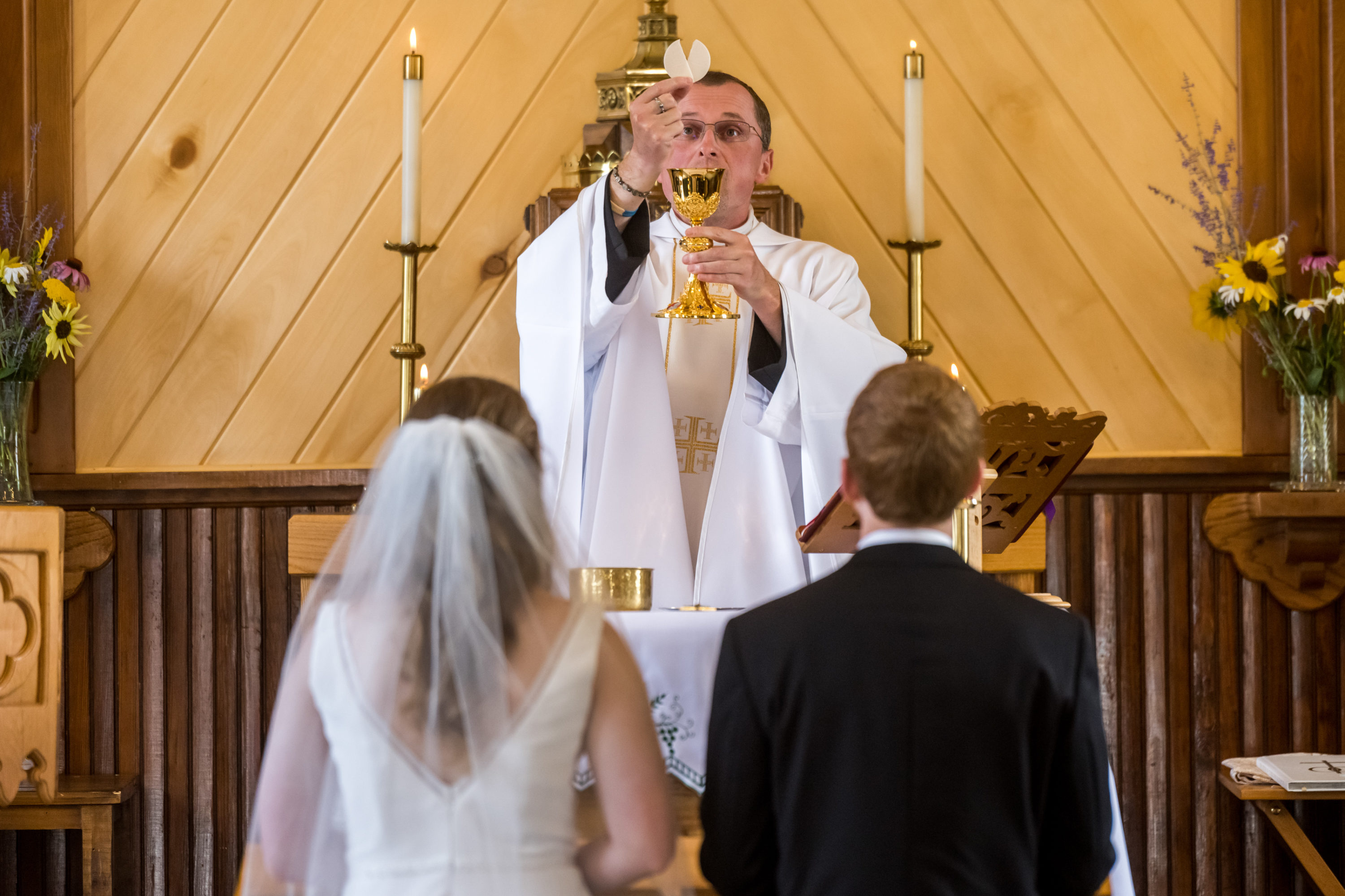 The priest holds a consecrated host and wine during a wedding at St. Patrick's Church Telluride.