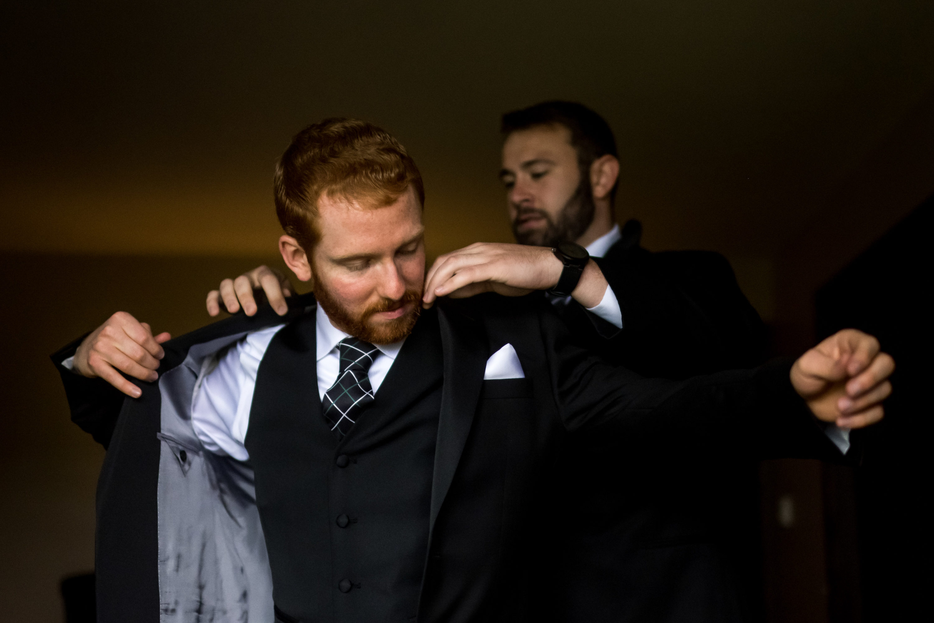 A groomsman helps the groom get into his suit jacket before his Telluride, Colorado, wedding.