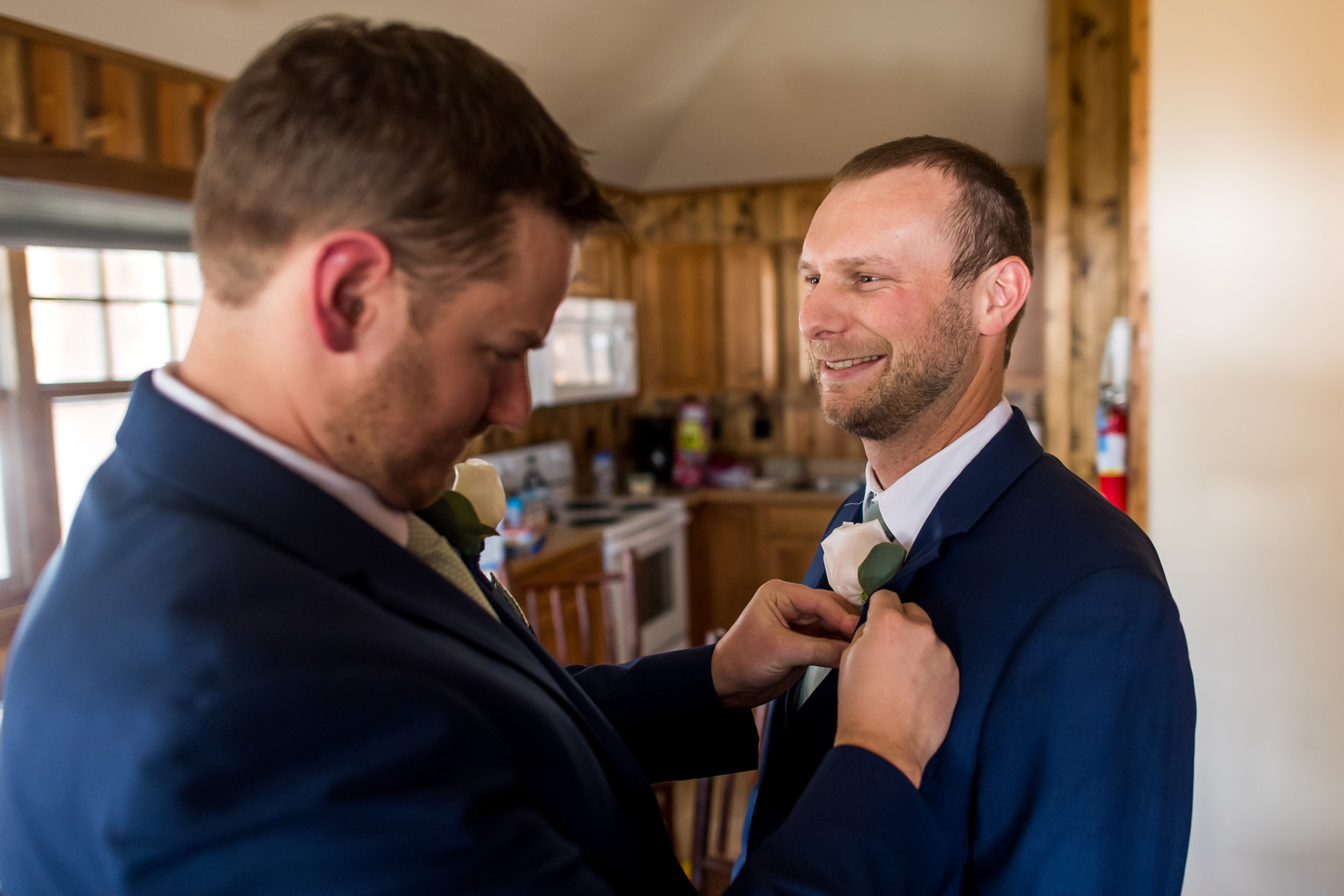 The groom pins on a boutonniere during his YMCA of the Rockies wedding in Estes Park, Colorado.