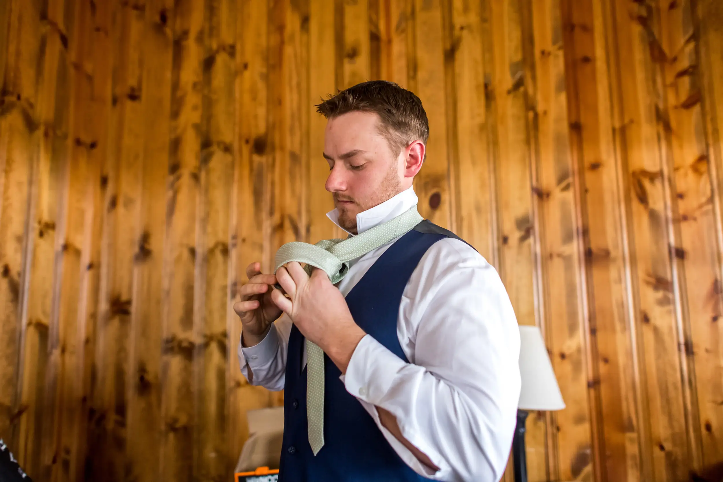 The groom adjusts his tie during his YMCA of the Rockies wedding in Estes Park, Colorado.