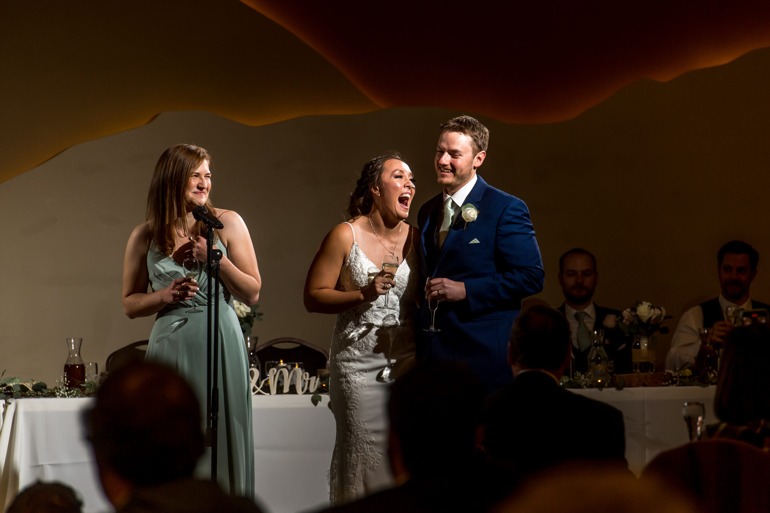 Bride and groom laugh during toasts during their YMCA of the Rockies wedding in Estes Park, Colorado.