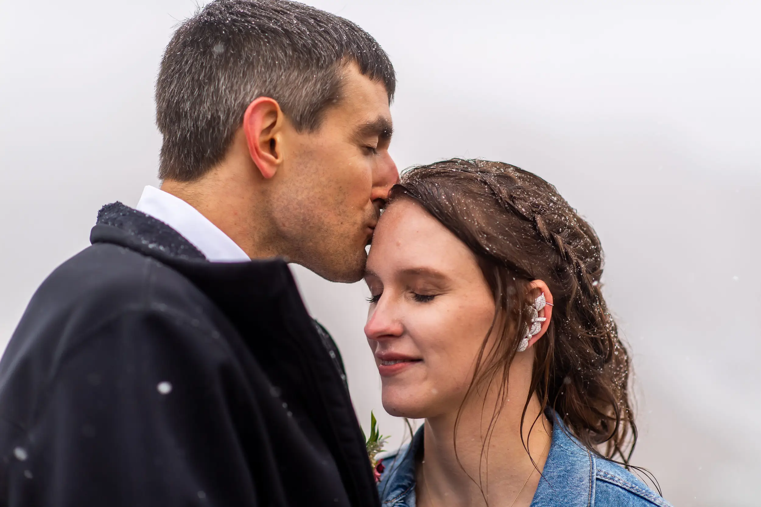 Andrew kisses Liz during their Roxborough State Park wedding at Lyons Overlook in the snow.