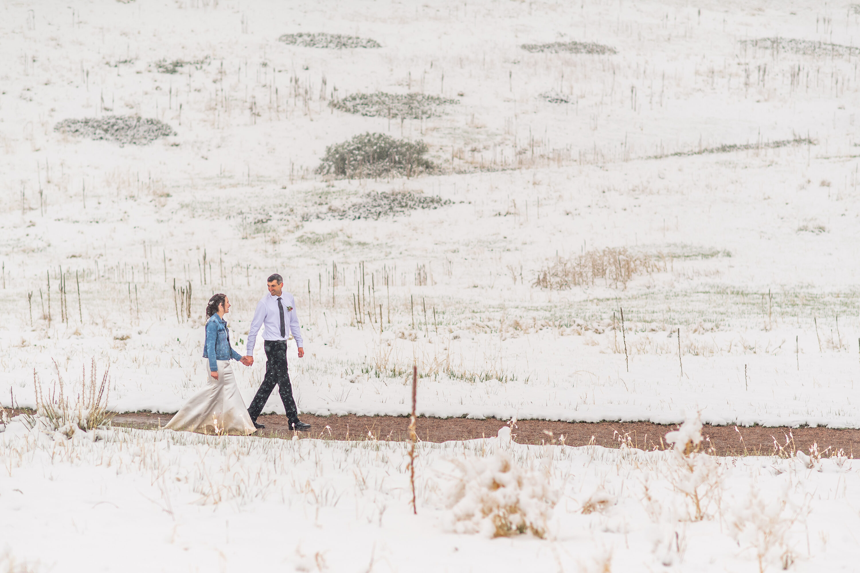 Andrew and Liz walk after their Roxborough State Park wedding at Lyons Overlook in the snow.