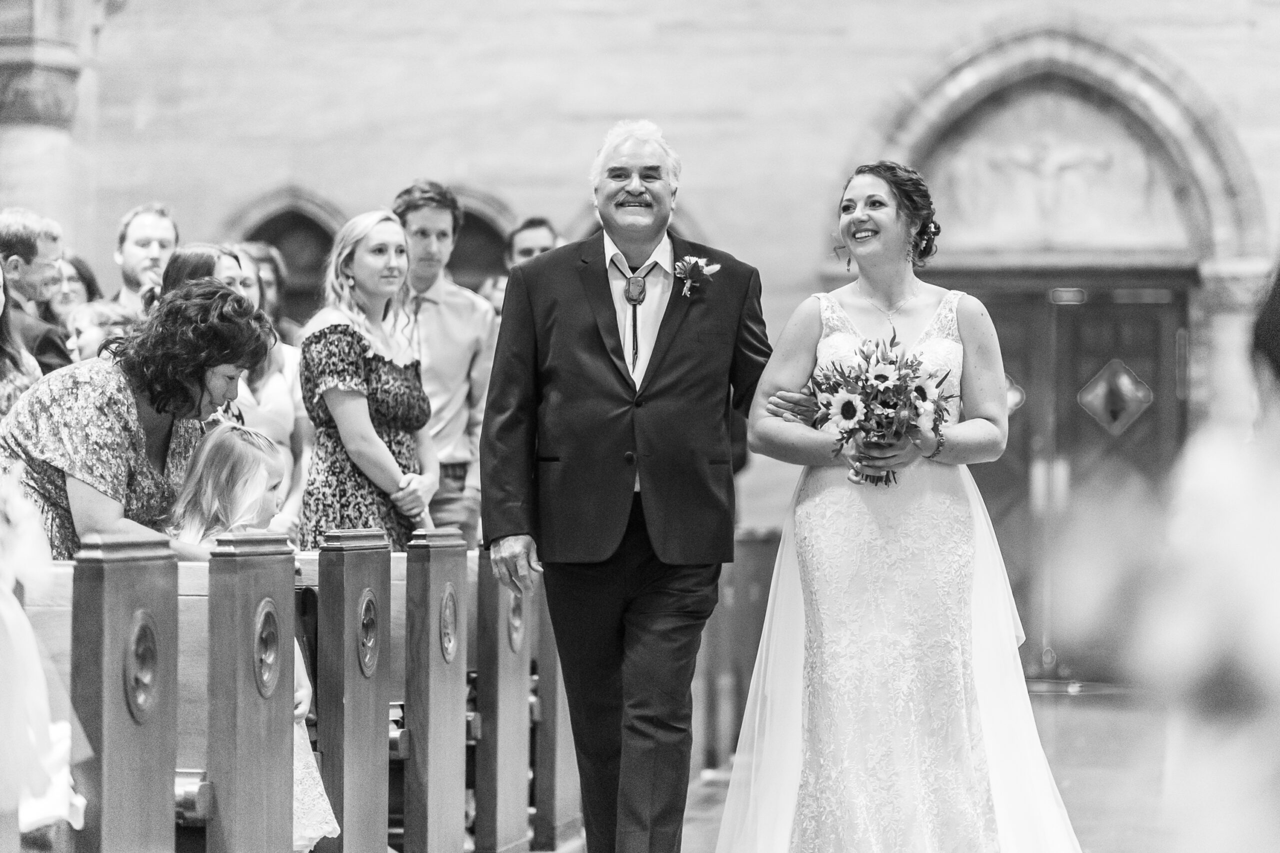 A bride walks down the aisle with her father during a Holy Ghost Church Denver wedding in Denver, Colorado.