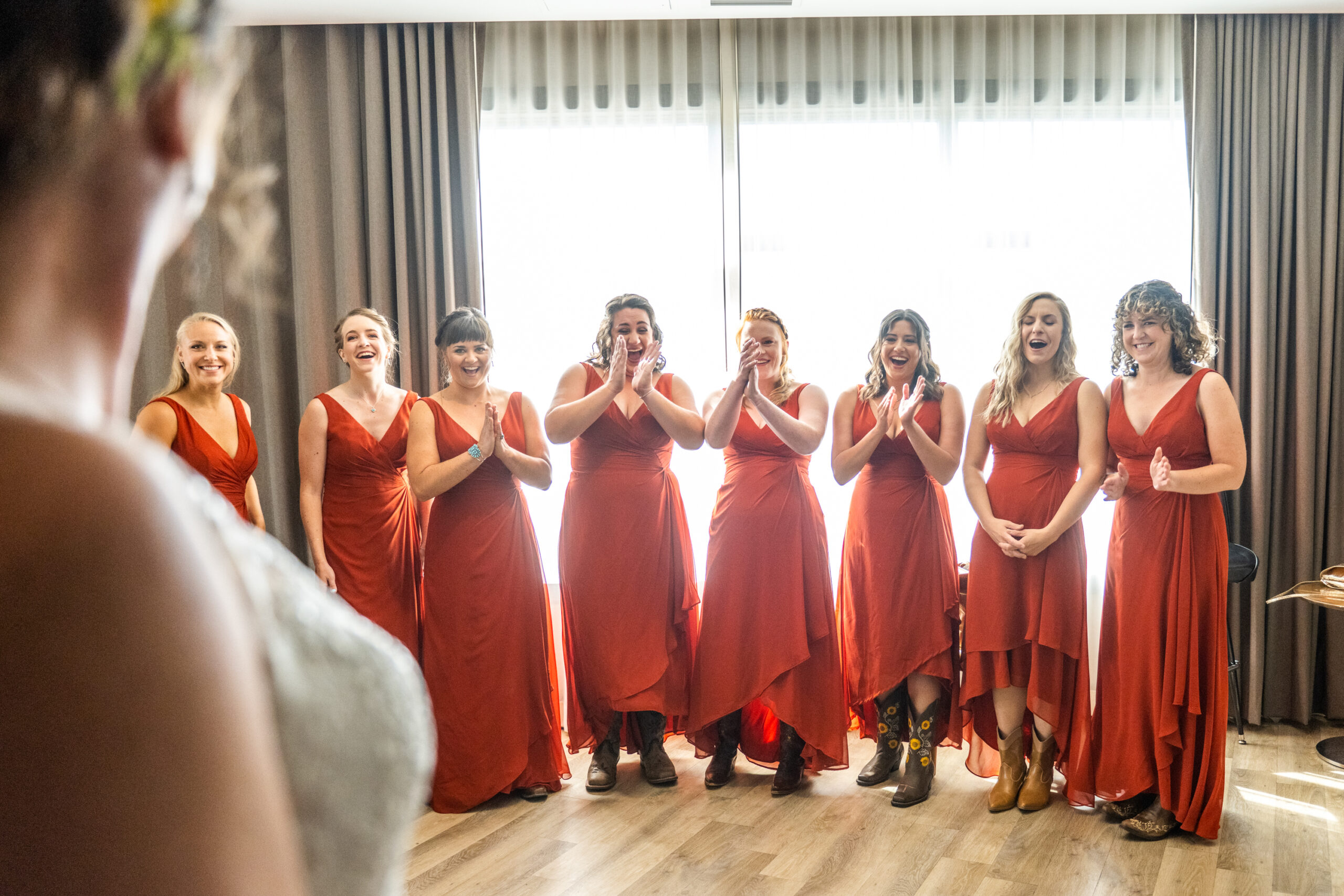 Bridesmaids applaud a bride when she turns around in her dress during a Holy Ghost Church Denver wedding in Denver, Colorado.