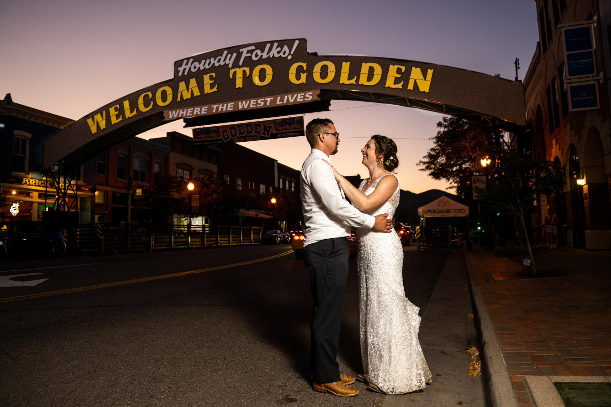 A bride and groom pose in front of the Golden, Colorado, welcome sign outside the Rose Event Center during their wedding reception.