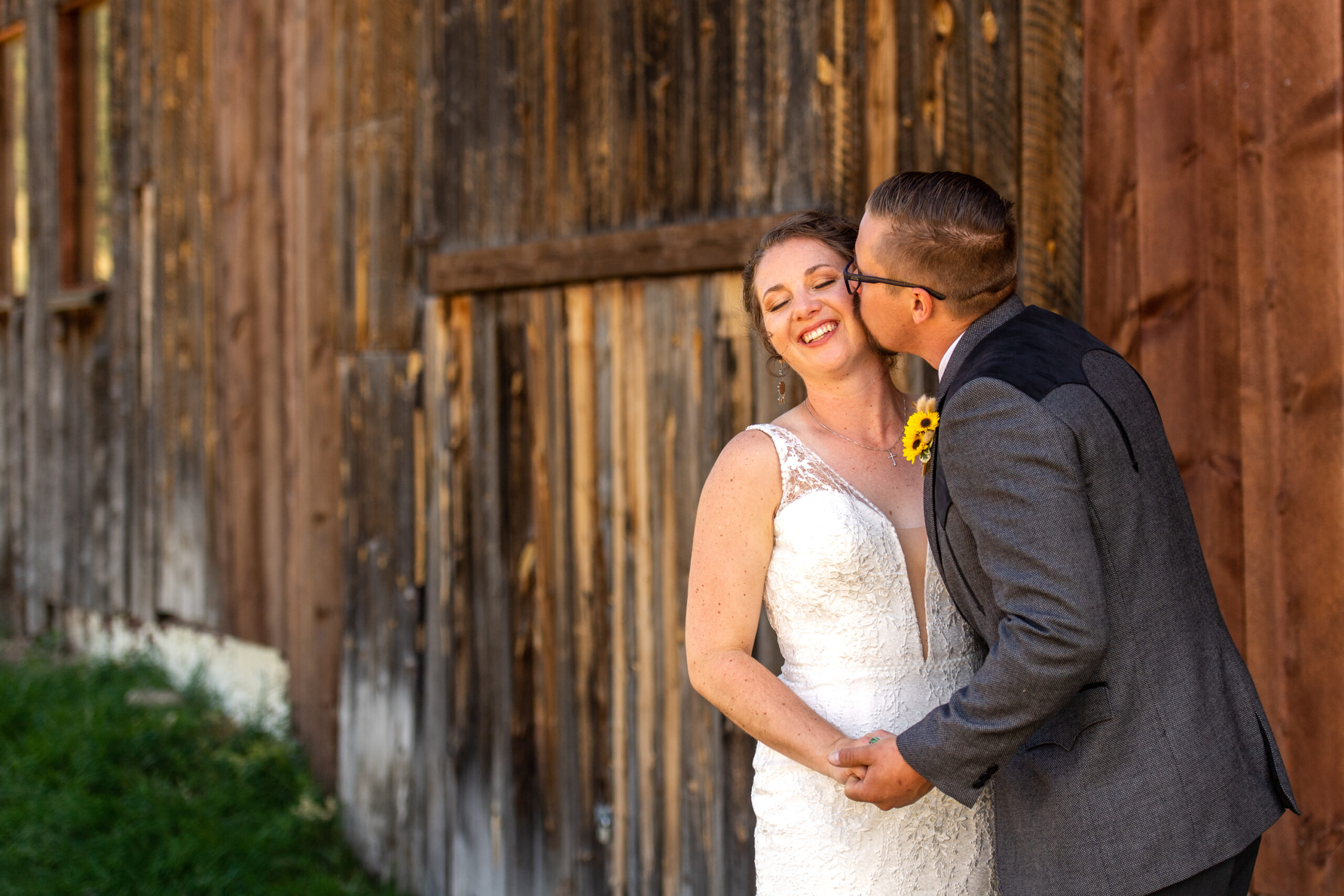 A groom kisses the side of his bride's face near the bar at Three Sisters Park in Evergreen, Colorado.