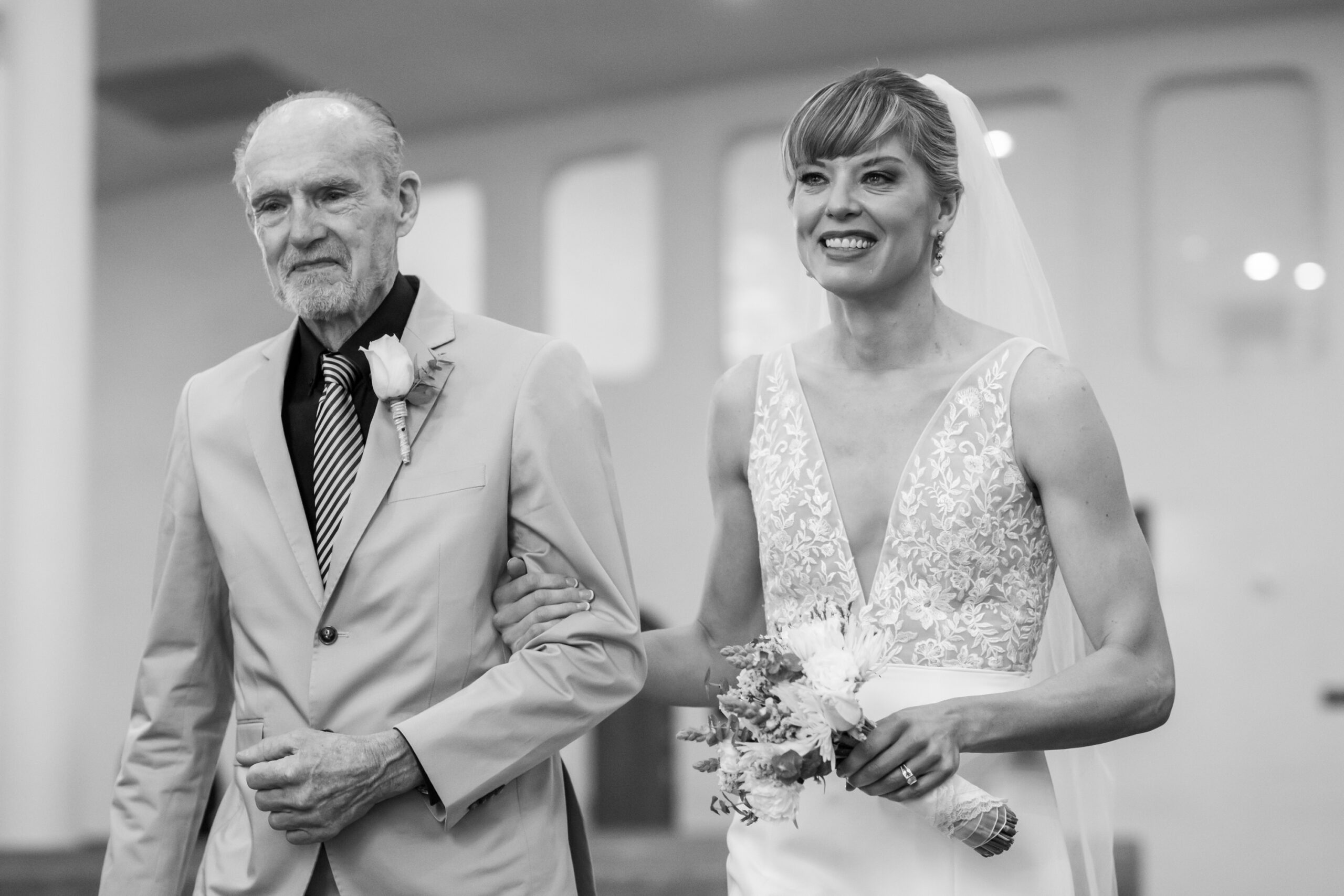 The bride walks down the aisle with her father during her Risen Christ Church Denver wedding in Denver, Colorado.
