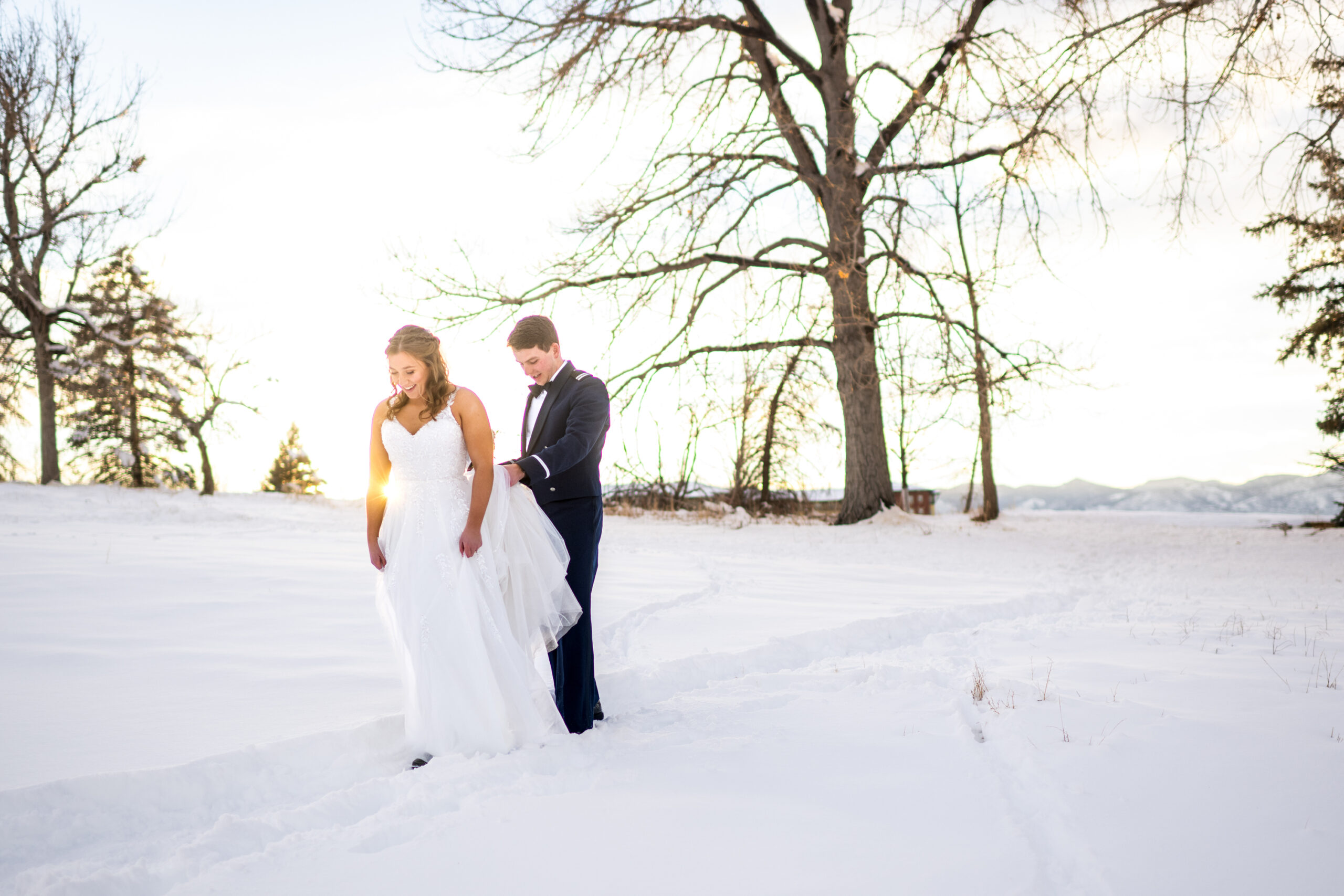The bride and groom walk in freshly fallen snow at Fly'n B Park in Littleton, Colorado, during their wedding at Ashley Ridge by Wedgewood Weddings.