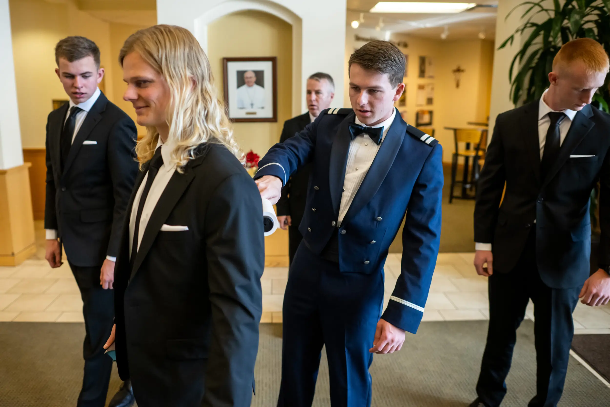 Michael brushes lint of a groomsman's suit before his St. Thomas More Catholic Church wedding in Centennial, Colorado.