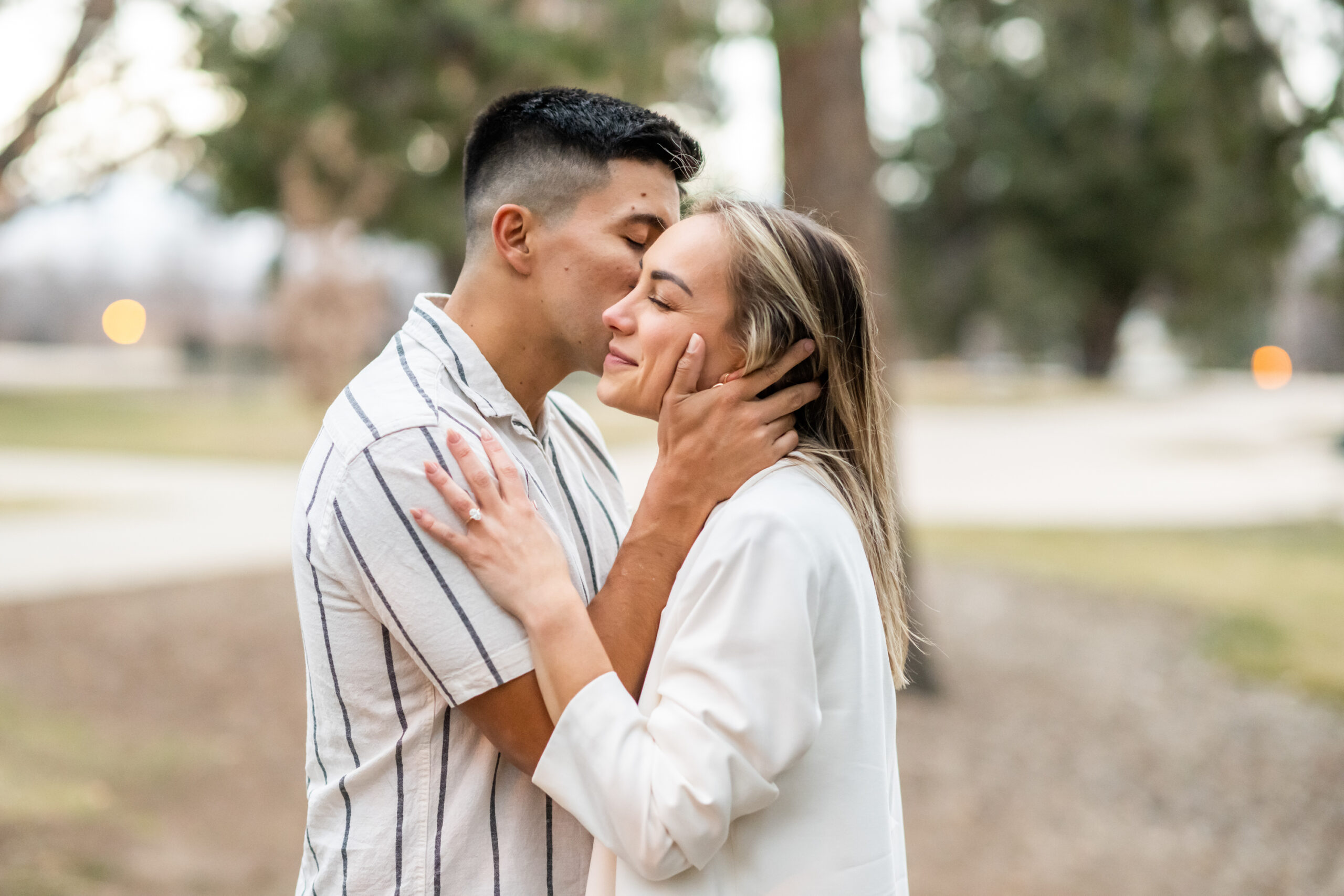 Nick and Codi kiss after a Cheesman Park secret proposal in Denver, Colorado.
