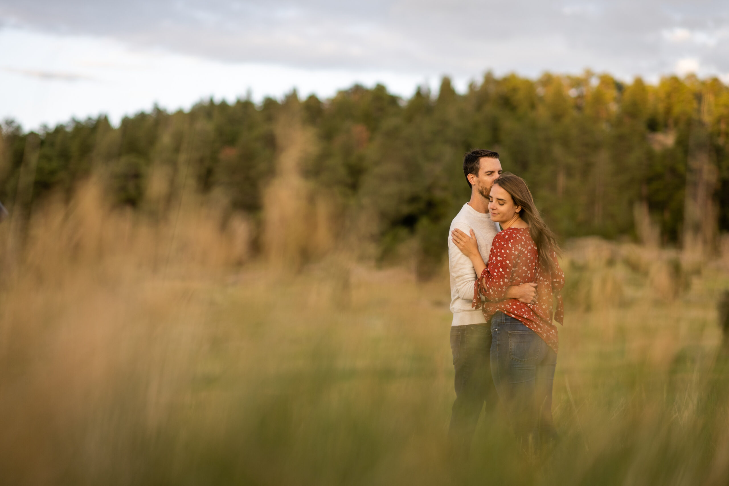 Alice and Joe hug during an engagement photo shoot at Three Sisters Park in Evergreen, Colorado.