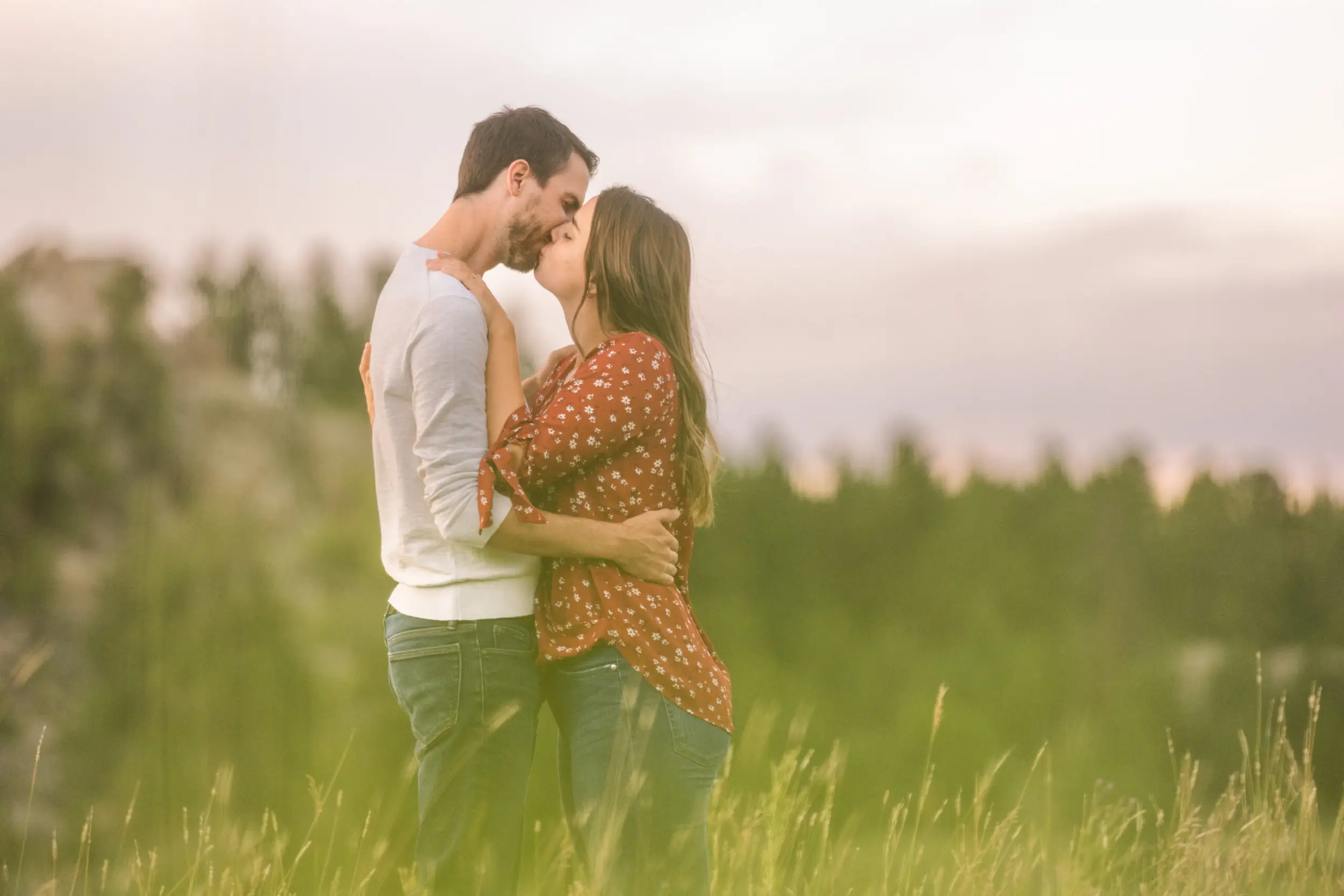 Alice and Joe kiss during an engagement photo shoot at Three Sisters Park in Evergreen, Colorado.