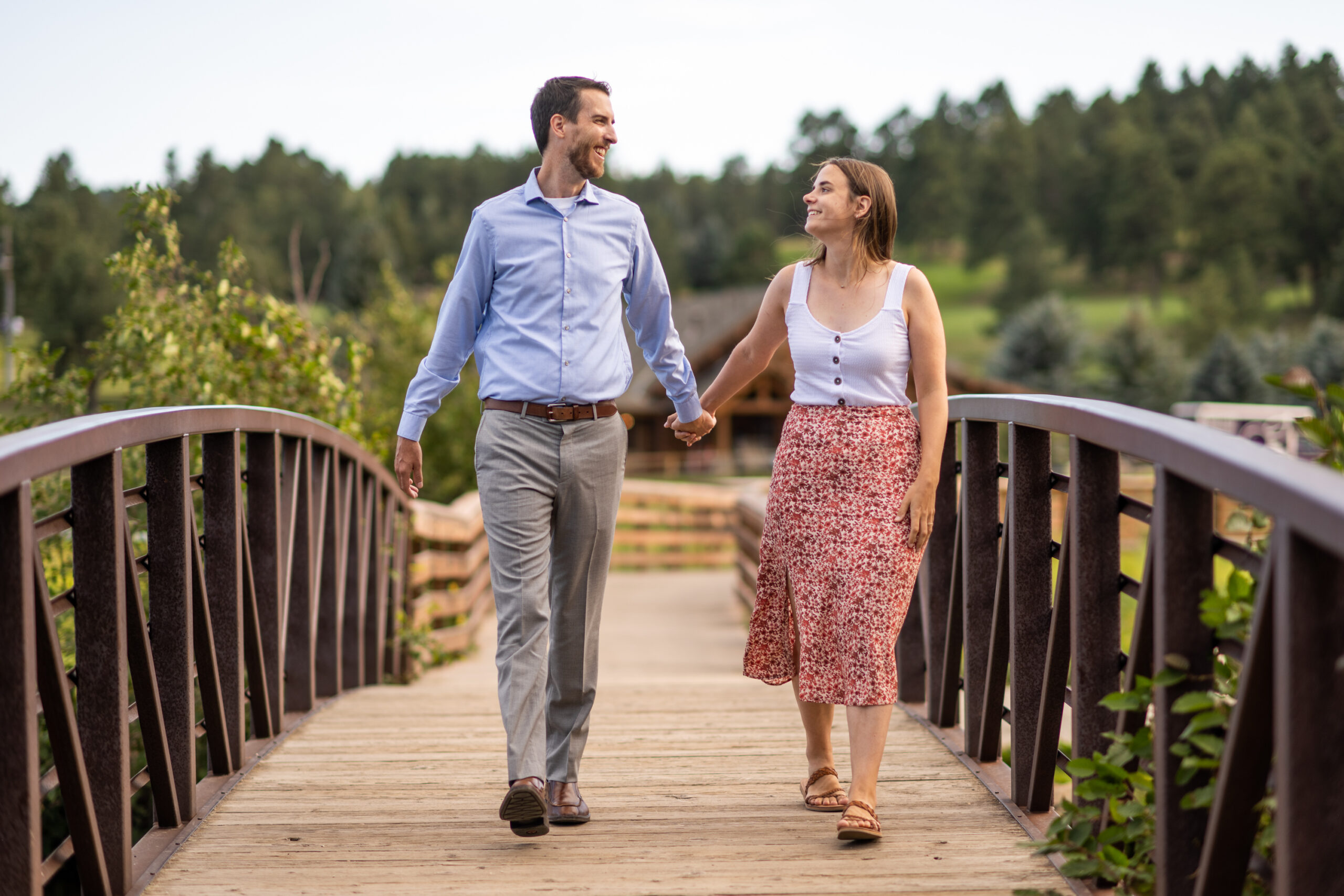 Alice and Joe hold hands on a bridge during an engagement photo shoot at Evergreen Lake in Evergreen, Colorado.