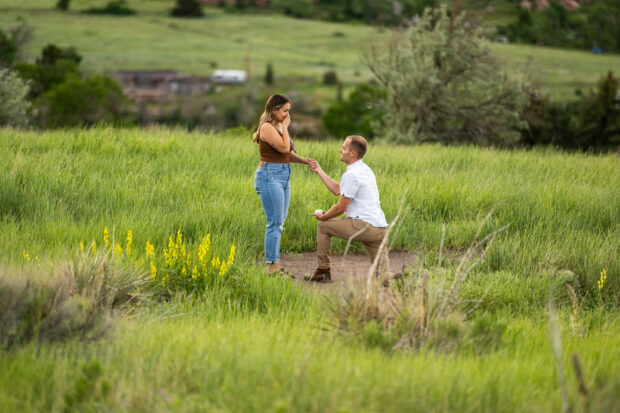 Ryan gets down on one knee before Elizabeth during a surprise proposal at Mt. Falcon Park West Trailhead near Denver, Colorado.