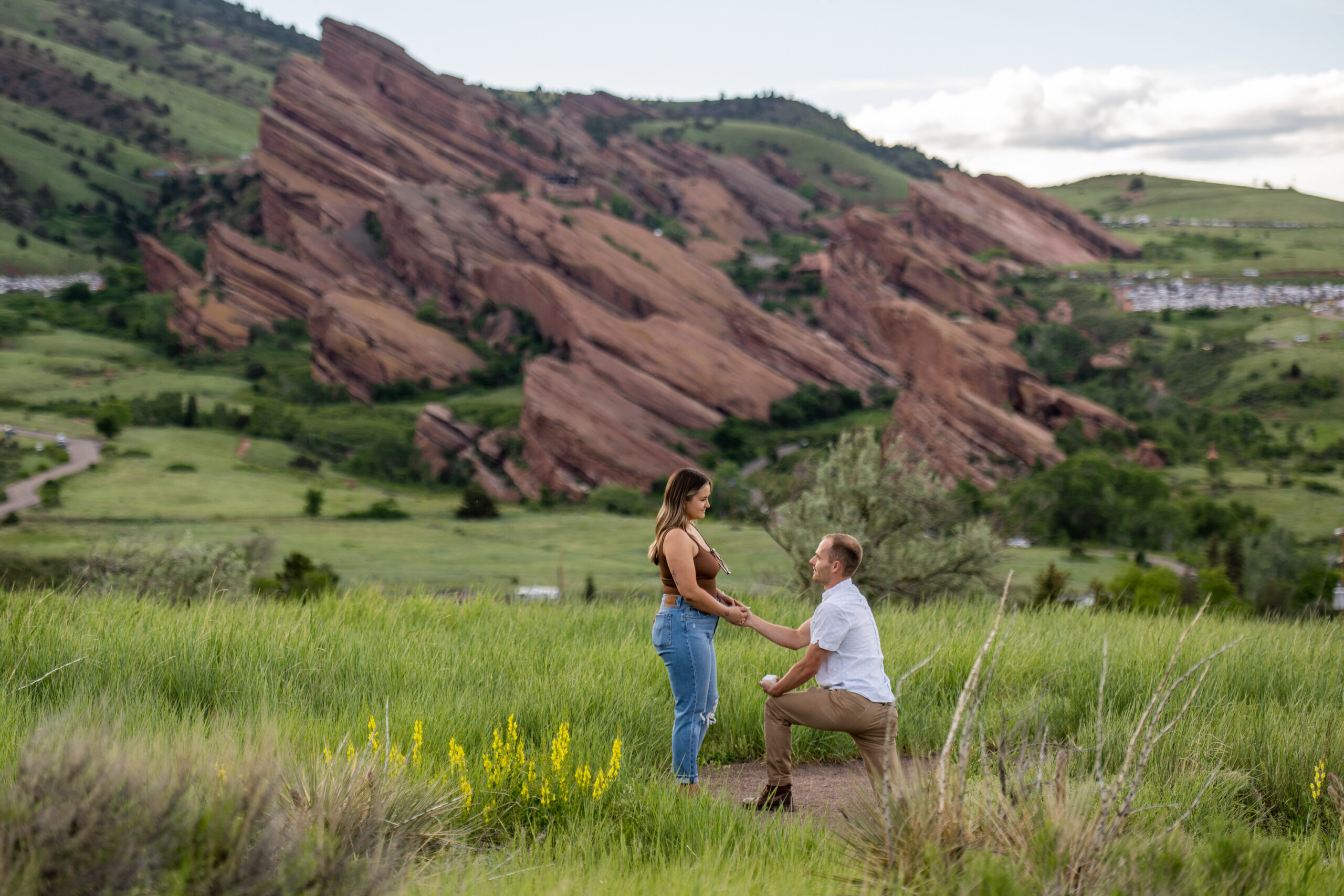 Ryan gets down on one knee before Elizabeth during a surprise proposal at Mt. Falcon Park East Trailhead near Denver, Colorado.