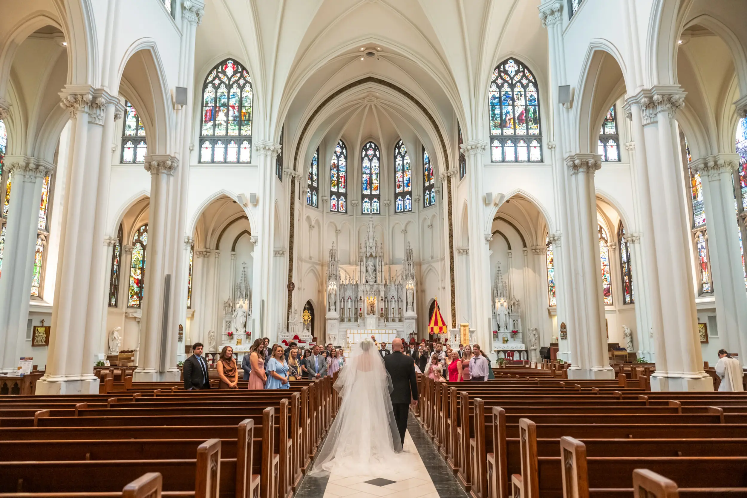The bride, right, and her father, left, walk down the aisle for her wedding at the Cathedral Basilica of the Immaculate Conception in Denver, Colorado.