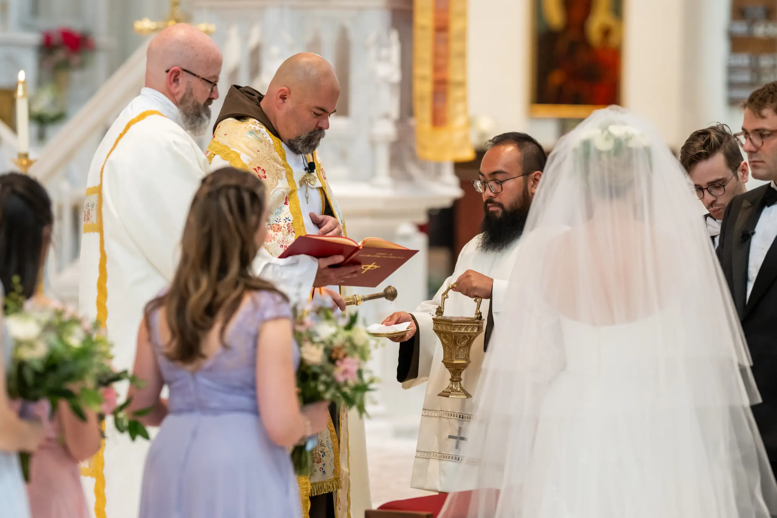 The priests blesses the rings with holy water at a wedding at the Cathedral Basilica of the Immaculate Conception in Denver, Colorado.