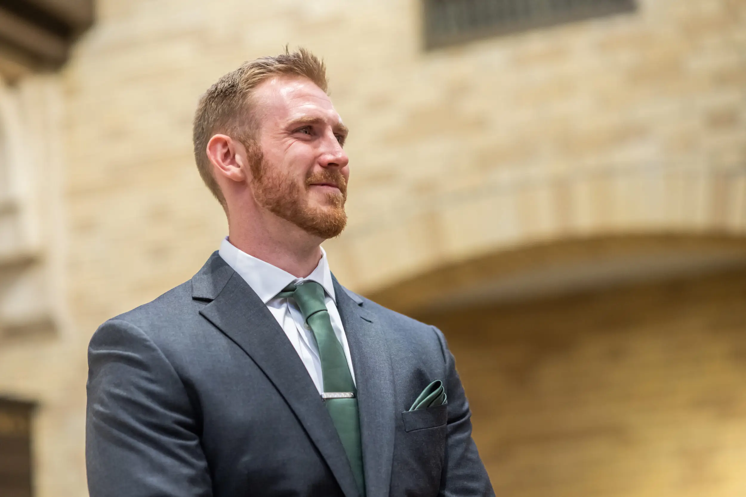 The groom looks on as the bride prepares to walk down the aisle for their wedding Mass at Our Lady of Lourdes Catholic Church in Denver, Colorado.
